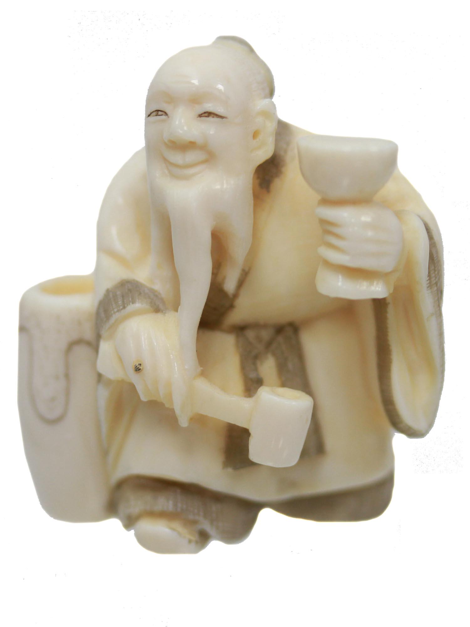 ANTIQUE HAND CARVED JAPANESE NETSUKE MAN W GOBLET: An antique Japanese hand-carved, engraved, inked from natural materials netsuke, depicting an old smiling man holding a goblet and a ladle in his hands, and standing near the barrel. There are two cor