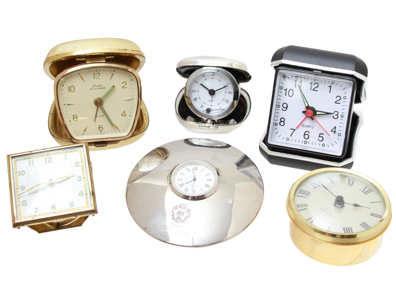 A LOT OF SIX VINTAGE TRAVEL ALARM CLOCKS: A collection of six vintage travel alarm clocks from various brands, including the clock by Heco, Lenox, Linden Black Forest, the clock engraved: Mairie de Nice, and others. Dimensions: Smallest: H: 2