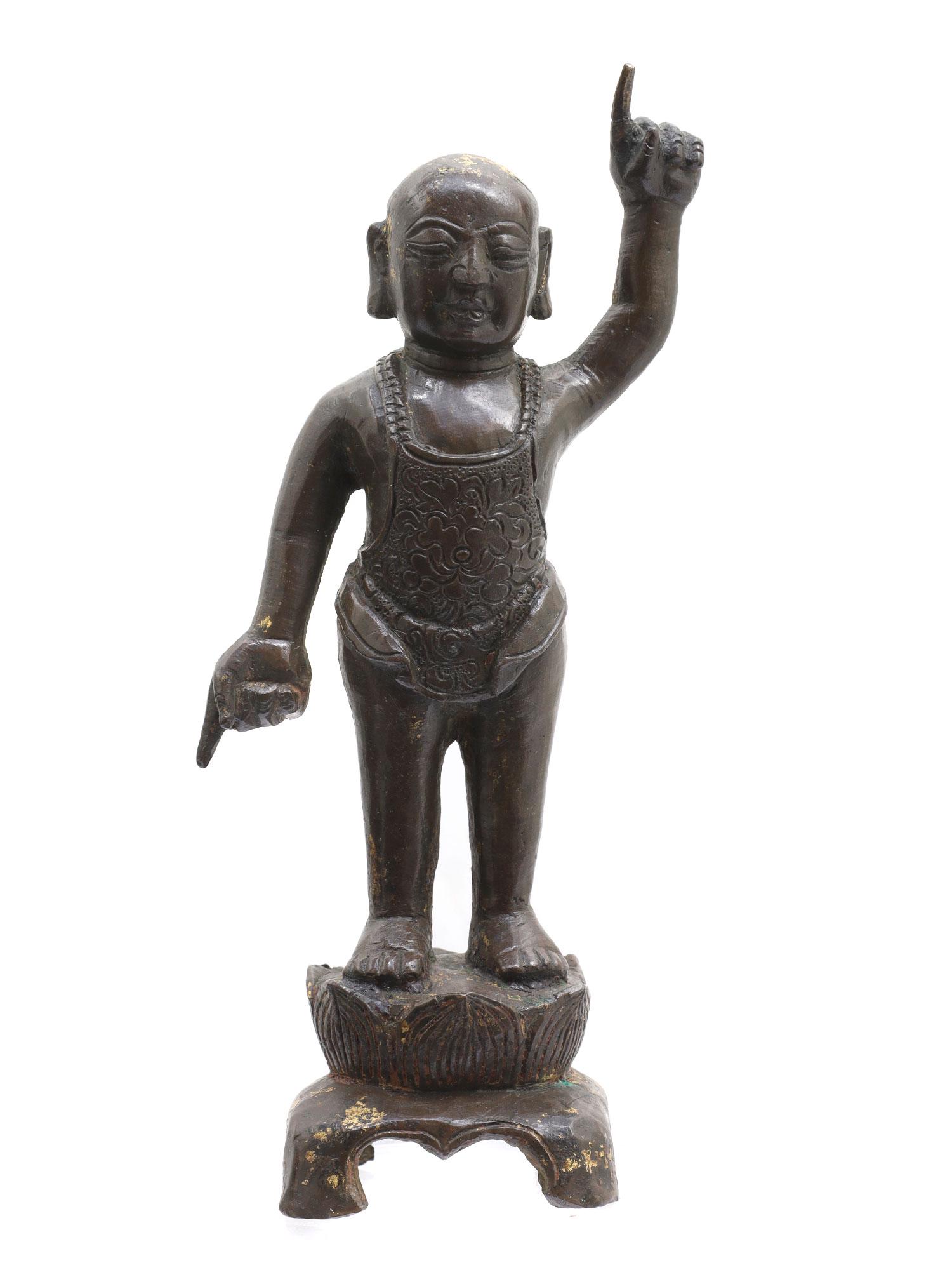 A BRONZE BUDDHA AS A CHILD, INDIA, 7-8 CC AD.: Antique Kashmir bronze figure depicting a baby Buddha with his left hand raised to the sky and his right hand lowered to the ground. The robe of the Buddha is engraved with floral motifs. There are sm
