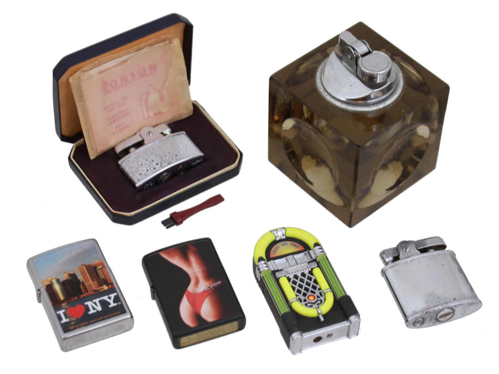 VINTAGE FIRE LIGHTERS MODERNIST AND NOVELTY ITEMS: A lot of vintage fire lighters. Consists a Ronson cigarette lighter with a bush and instruction papers in a case, a brown JJJ Cut Glass Cube table fire lighter done in Japan dating early 1970s. A butt