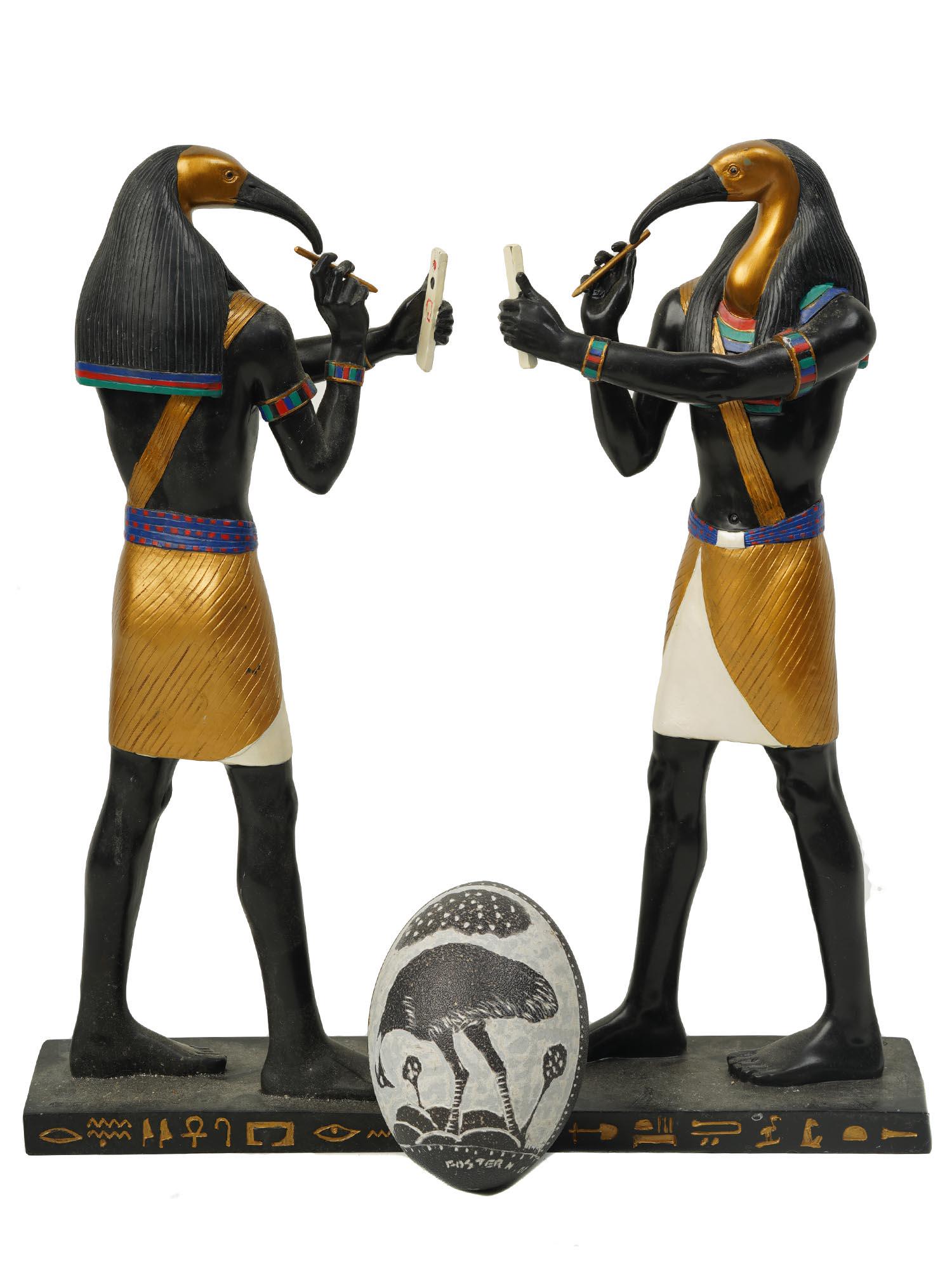 TWO THOTH SCULPTURES AND A SCRIMSHAW OSTRICH EGG: A lot of two Thoth statues hand painted in bronze finish with a high-quality antique look. Thoth was an ancient Egyptian god of knowledge and wisdom. Also includes a decorated ostrich egg by Foster Nk