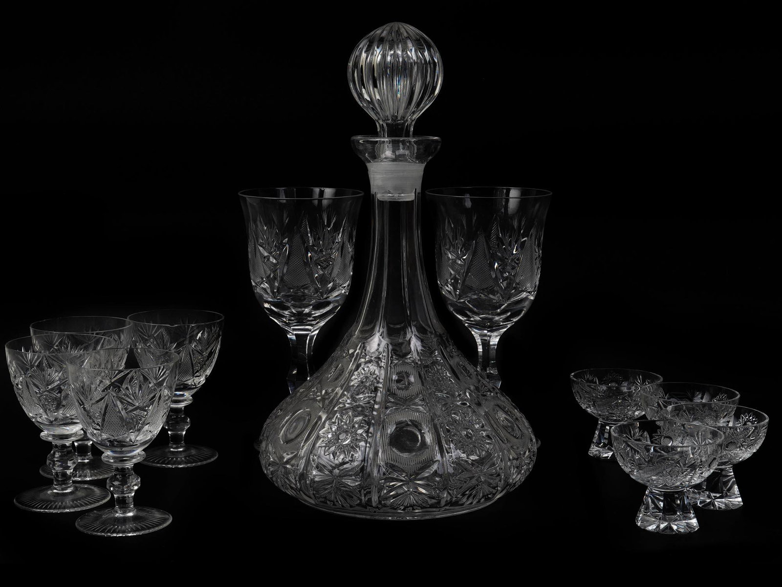 VINTAGE CRYSTAL CUT GLASS WARE SET OF 14 PIECES: A vintage classic glass ware set of fourteen pieces. The set includes a decanter with a stopper, four small glasses on a short leg, five glasses on a tall leg, and four tall wine glasses. Each item is