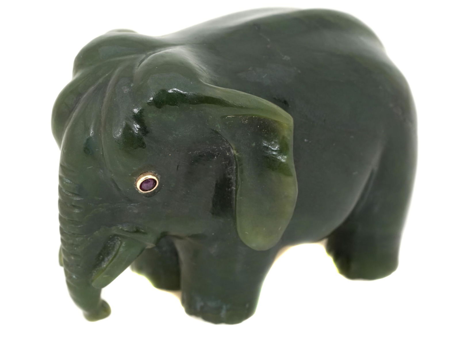 A RUSSIAN CARVED NEPHRITE JADE ELEPHANT FIGURINE: A Russian hand carved from Nephrite Jade figurine in the shape of an elephant. The figurine is inlaid with Ruby stone eyes in gold settings. Dimensions: 2" x 1 1/2" x 1" in. All measurements are appro