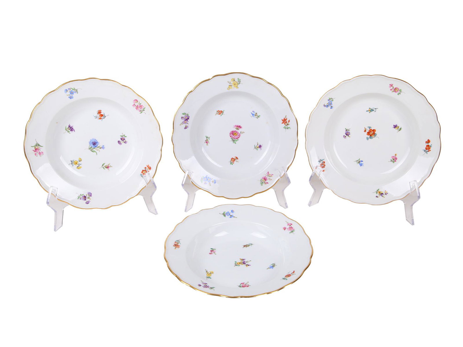 FOUR ANTIQUE 1900S MEISSEN PORCELAIN SOUP PLATES: Four antique porcelain soup plates manufactured by Meissen. The pieces are delicately hand painted with polychrome sprays of flowers and feature gilt rims throughout. Marked to the underside with blue