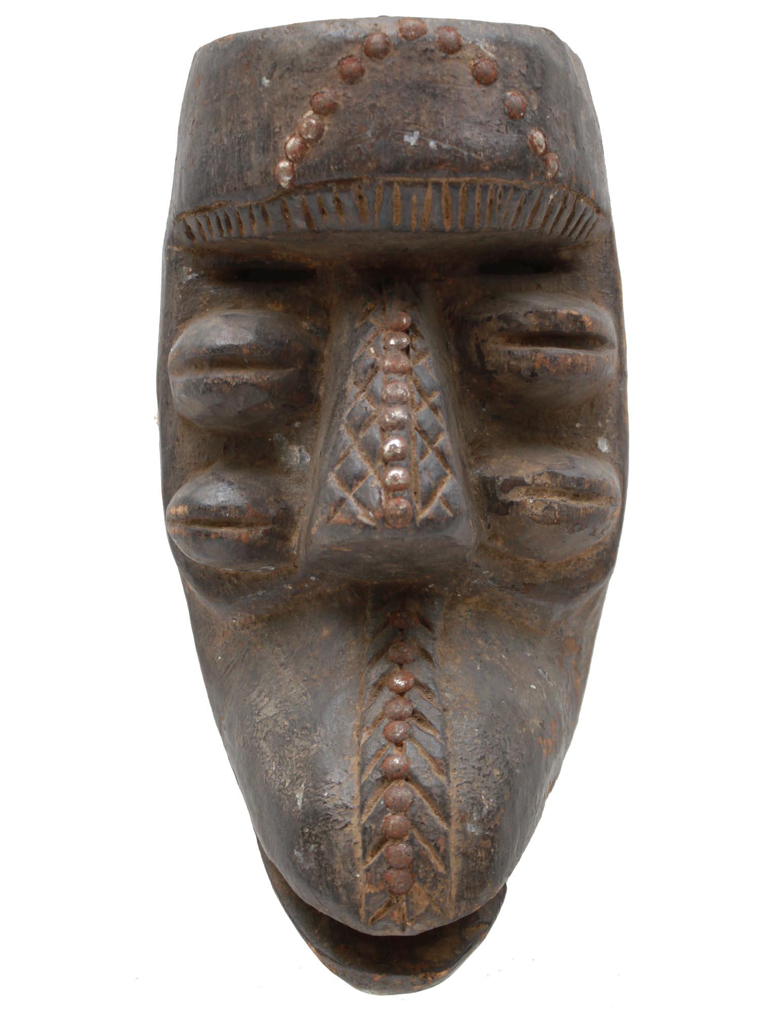 A VINTAGE AFRICAN WE/GUERRE MASK, IVORY COAST: An old hand-carved wooden mask from the Liberia/Ivory Coast. The mask, with its prominent forehead and nose, narrow eye slits, oval chin protrusions and a heavily curved beard, represents the spirit o