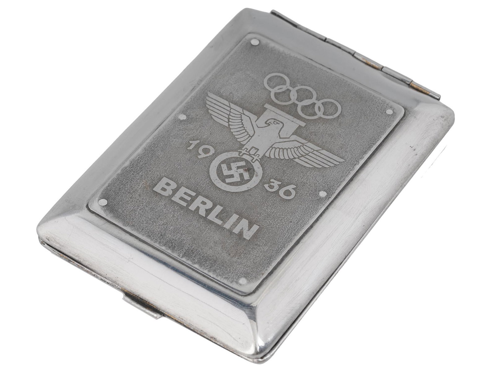 GERMAN NAZI 1936 OLYMPIC GAMES CIGARETTE CASE: A Pre WWII period commemorative white metal cigarette case from the 1936 Berlin Olympic games. The lid is decorated with a riveted plate inscribed: 1936 Berlin and depicting five Olympic rings and the