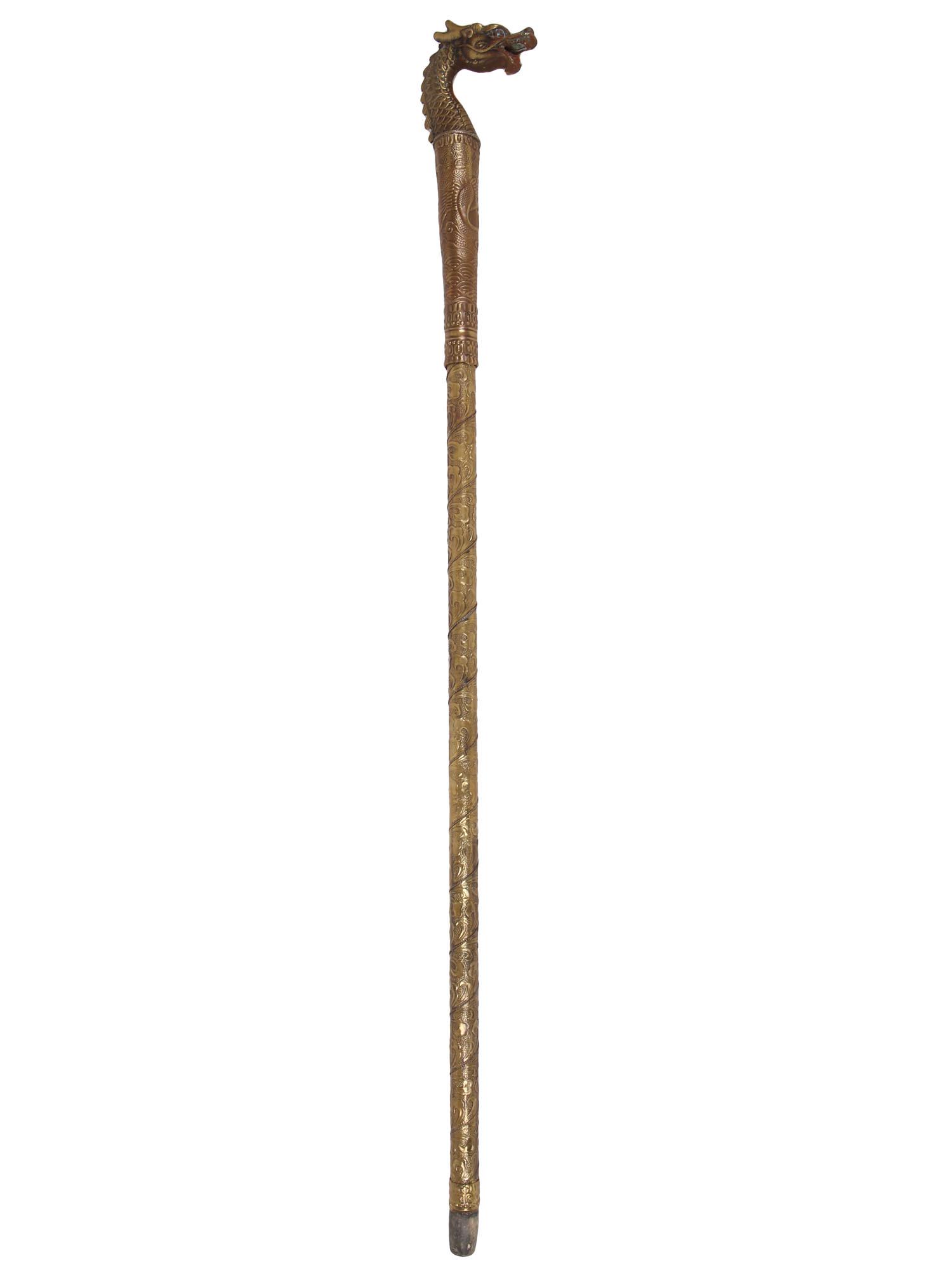 VINTAGE ASIAN DRAGON HEAD SWORD CANE: A vintage Asian brass cane with a steel sword hidden inside which can be accessed by unscrewing the handle. The cane shaft is richly decorated with the scrolling floral pattern. The head of the cane c