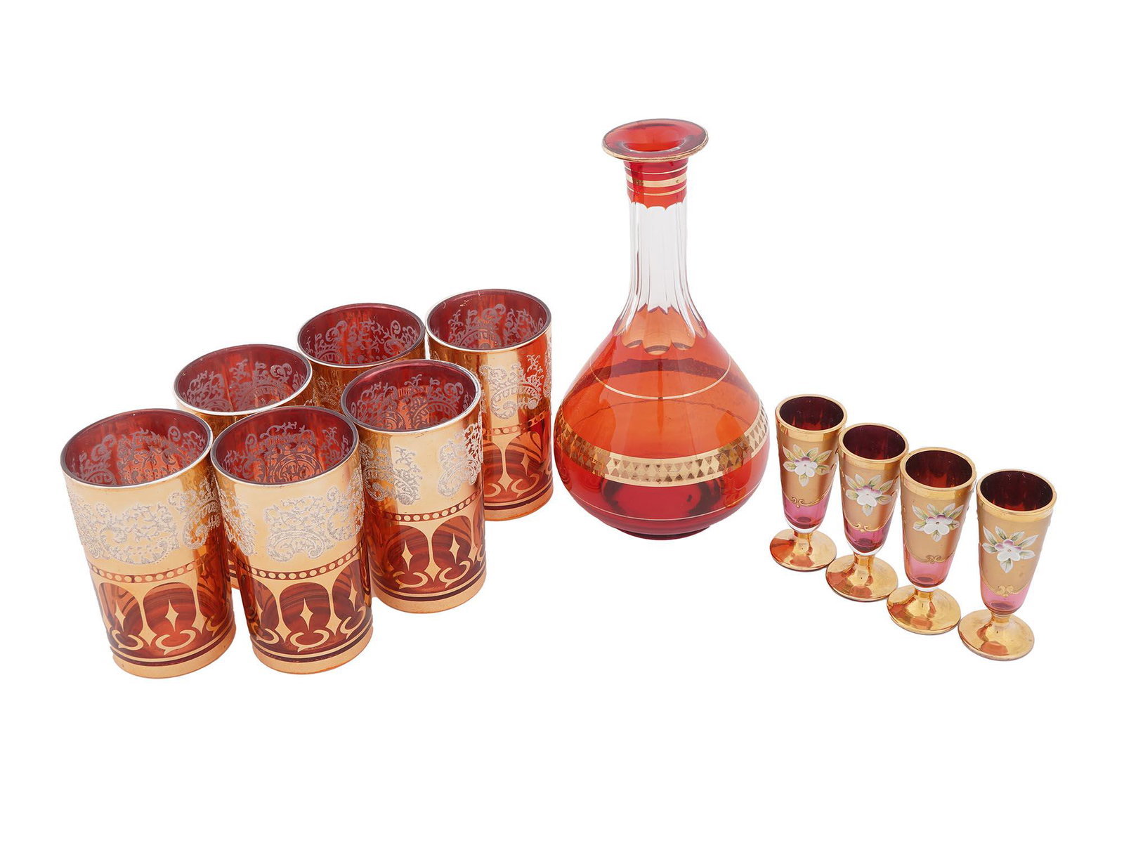 ITALIAN BOHEMIAN RUBY GILT GLASSES DECANTER SET: An Italian and Korean glass set of eleven pieces. The set includes a group of six red ruby and gilt glasses adorned with foliage and ornamental patterns, and marked, Made in Korea, on the bottom, a ru