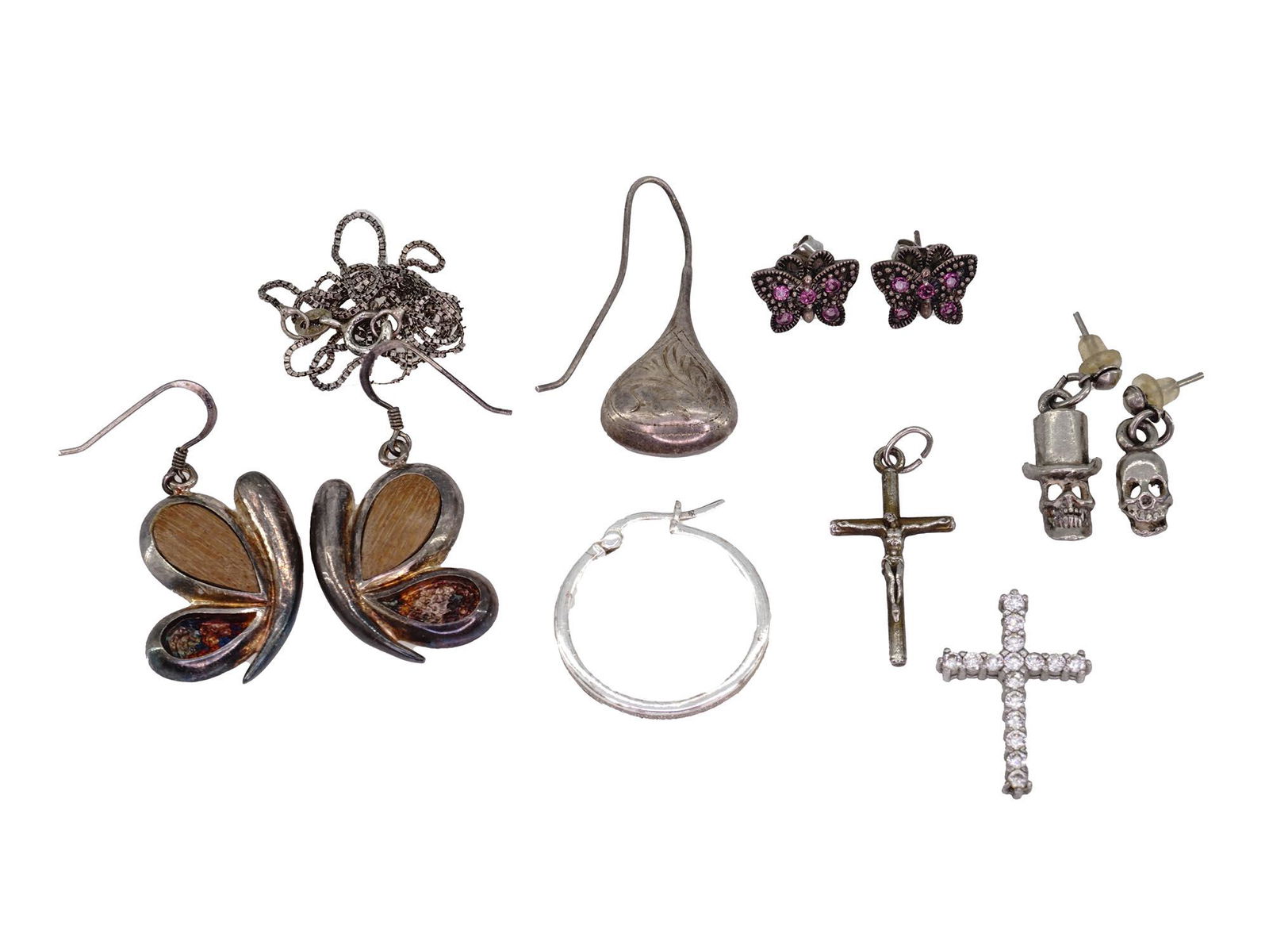 GROUP OF STERLING SILVER JEWELRY PIECES FOR WOMEN: The lot includes a pair of 925 silver Anna Sui butterfly earrings set with pink rhinestones, a 925 silver cross set with white rhinestones, a silver tone Crucifix, unmarked, a silver chain marked on t