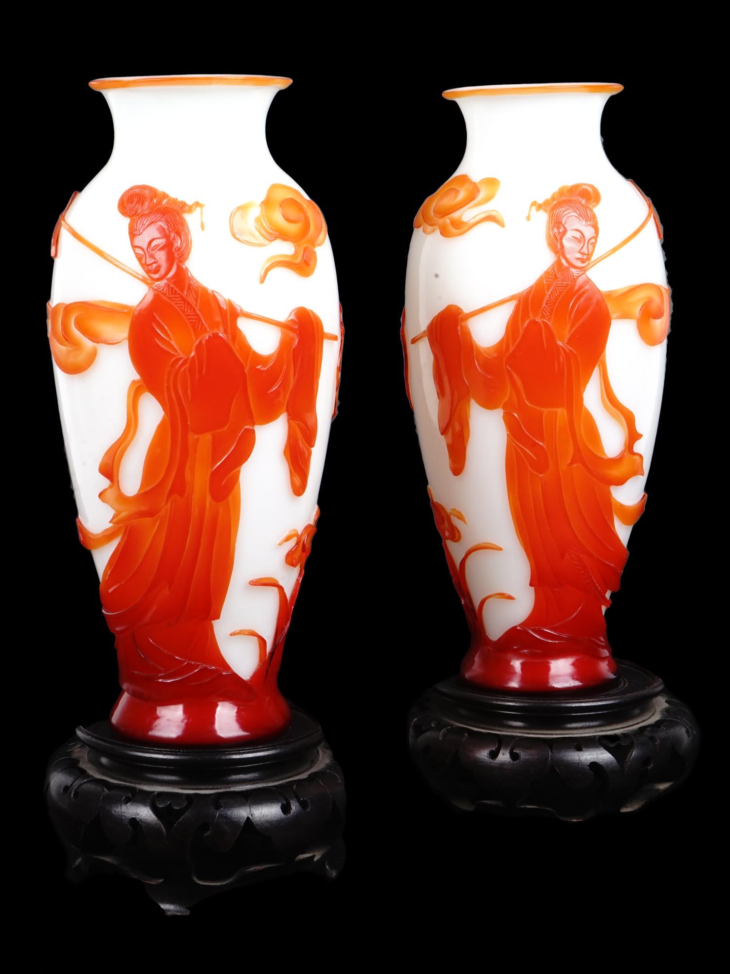 ANTIQUE CHINESE PEKING GLASS RED OVERLAY VASES: A pair of tall antique Chinese white Peking glass vases. The elongated shape of the vase resembles an amphora. The vases are adorned with red and orange cameo overlays depicting scenes with Guanyin an