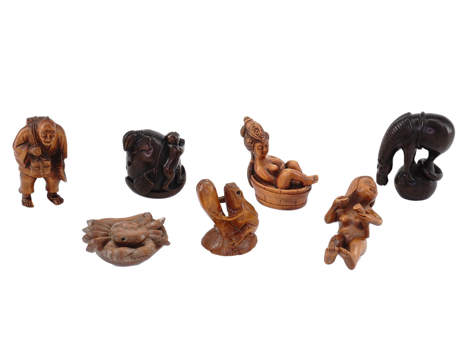 GROUP OF ANTIQUE JAPANESE CARVED NETSUKE FIGURINES: A group of small antique Japanese Meiji period hand carved wooden netsuke okimono figurines. The figurines depict a frog, a horse, a crab, several nude female figurines in erotic scenes, Hotei, one of