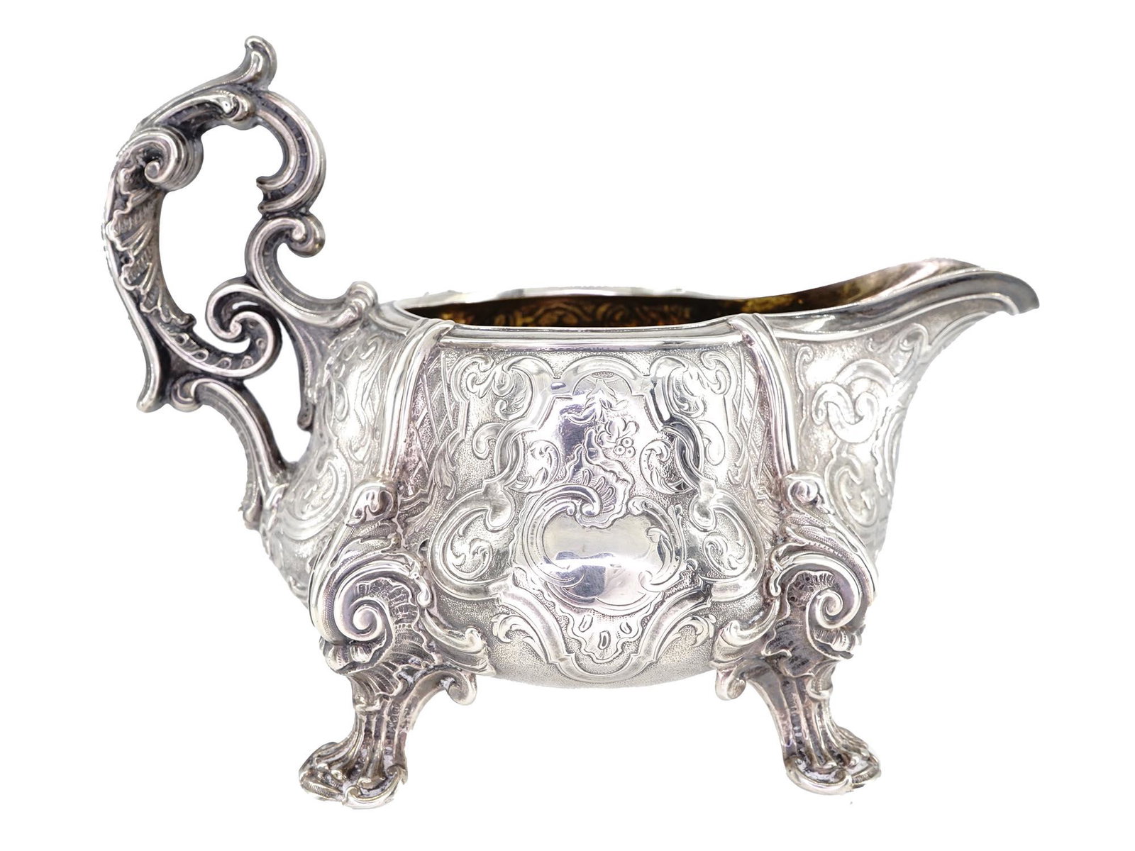 ANTIQUE FRENCH ODIOT PARIS FOOTED SILVER CREAMER: An antique French Odiot Paris original silver creamer adorned with four figural legs and a handle. A gilt wash interior. The exterior is decorated with foliage and scrollwork motifs made in the Repous
