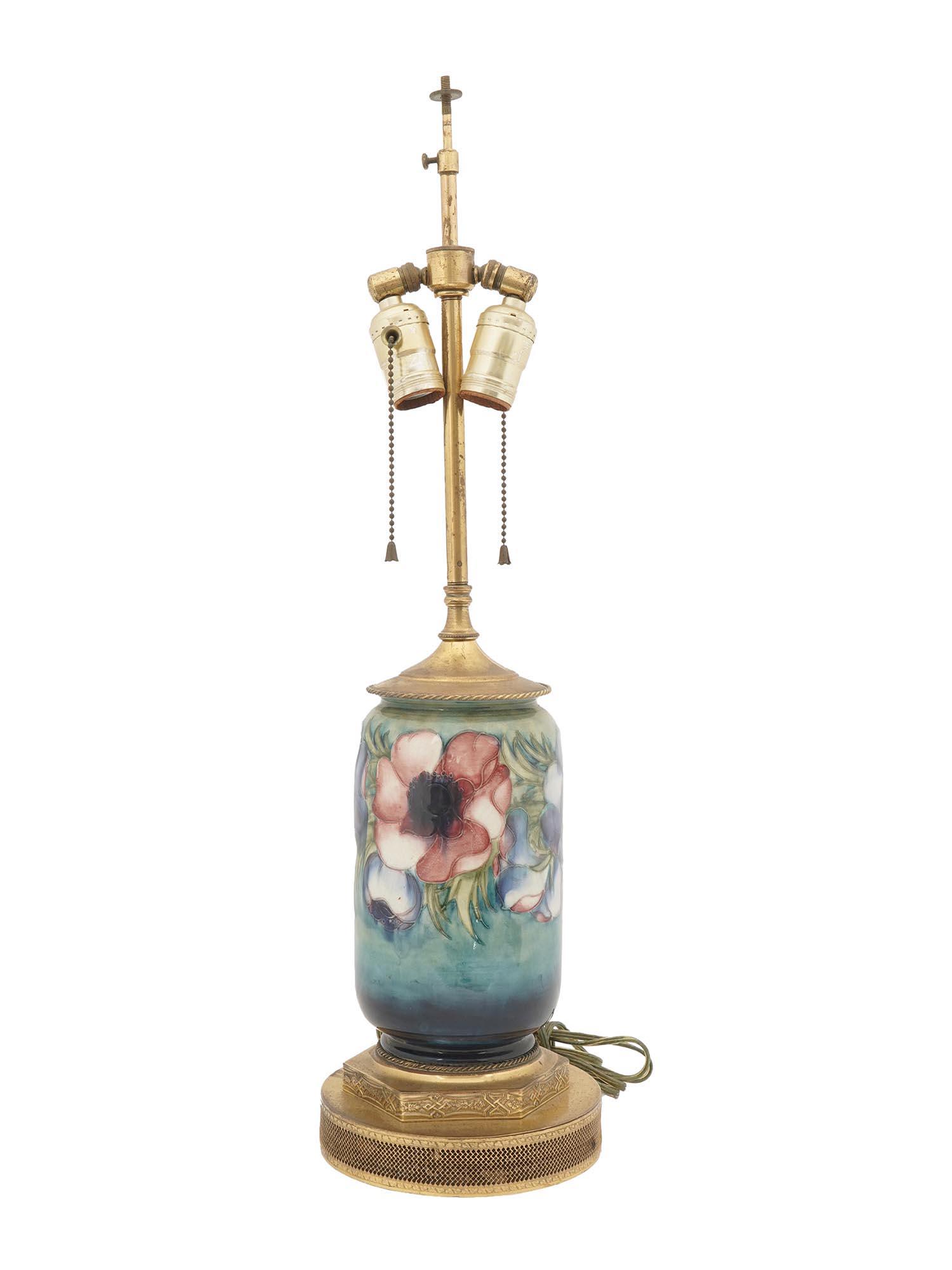 ANTIQUE PORCELAIN WITH GILT BRASS TABLE LAMP: An antique converted to an electrical table lamp with two light fixtures. The base and shaft of the lamp are made of gilt brass with ornamental metalwork. The elongated porcelain part is hand-painted