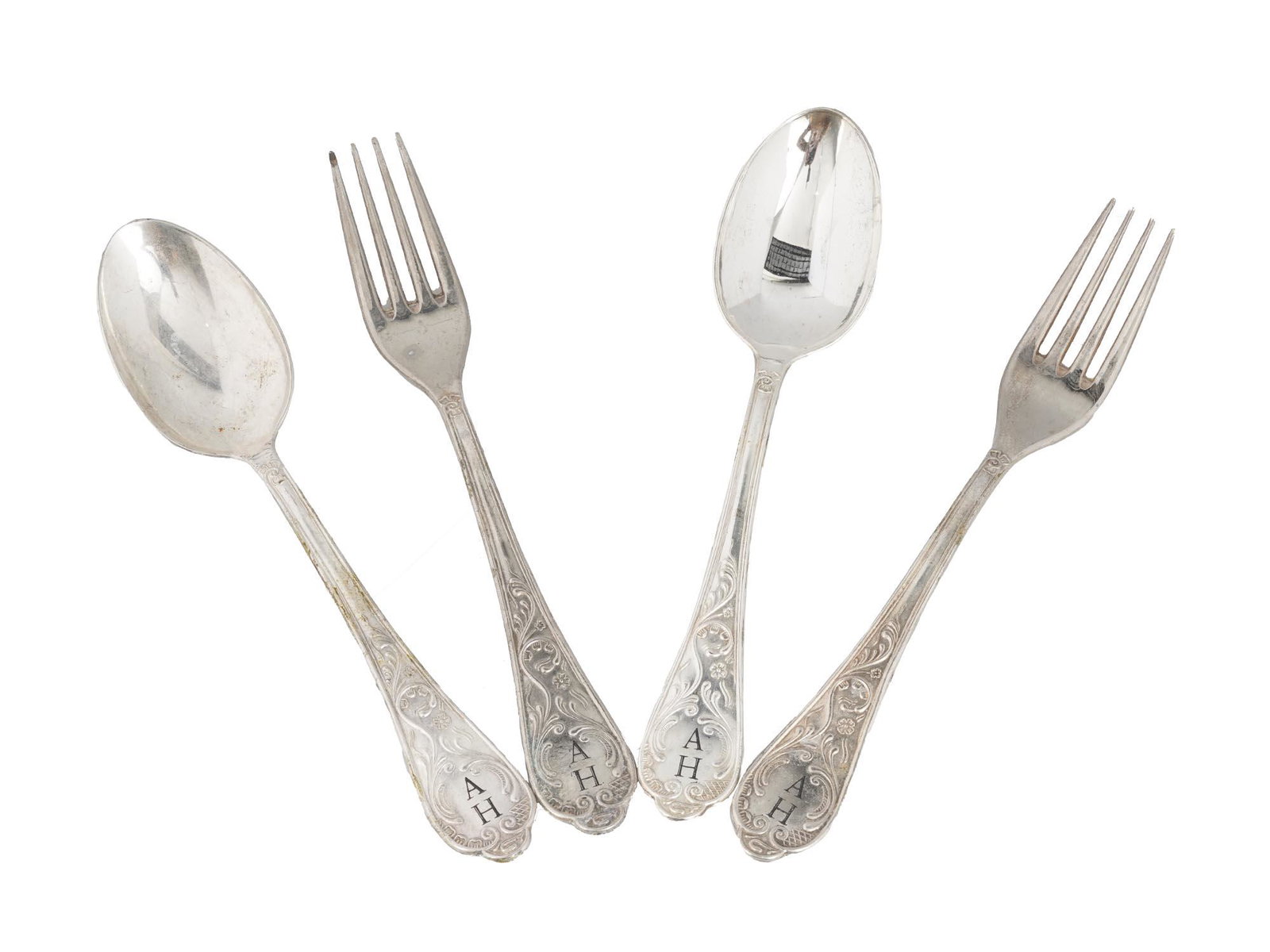 WWII SILVER CUTLERY SET W. ADOLF HITLER INITIALS: A silver cutlery set with two dinner spoons and forks. Each utensil is marked with 800 European silver standard. Handles are decorated with repousse floral motifs and black initials AH for Adolf Hitle