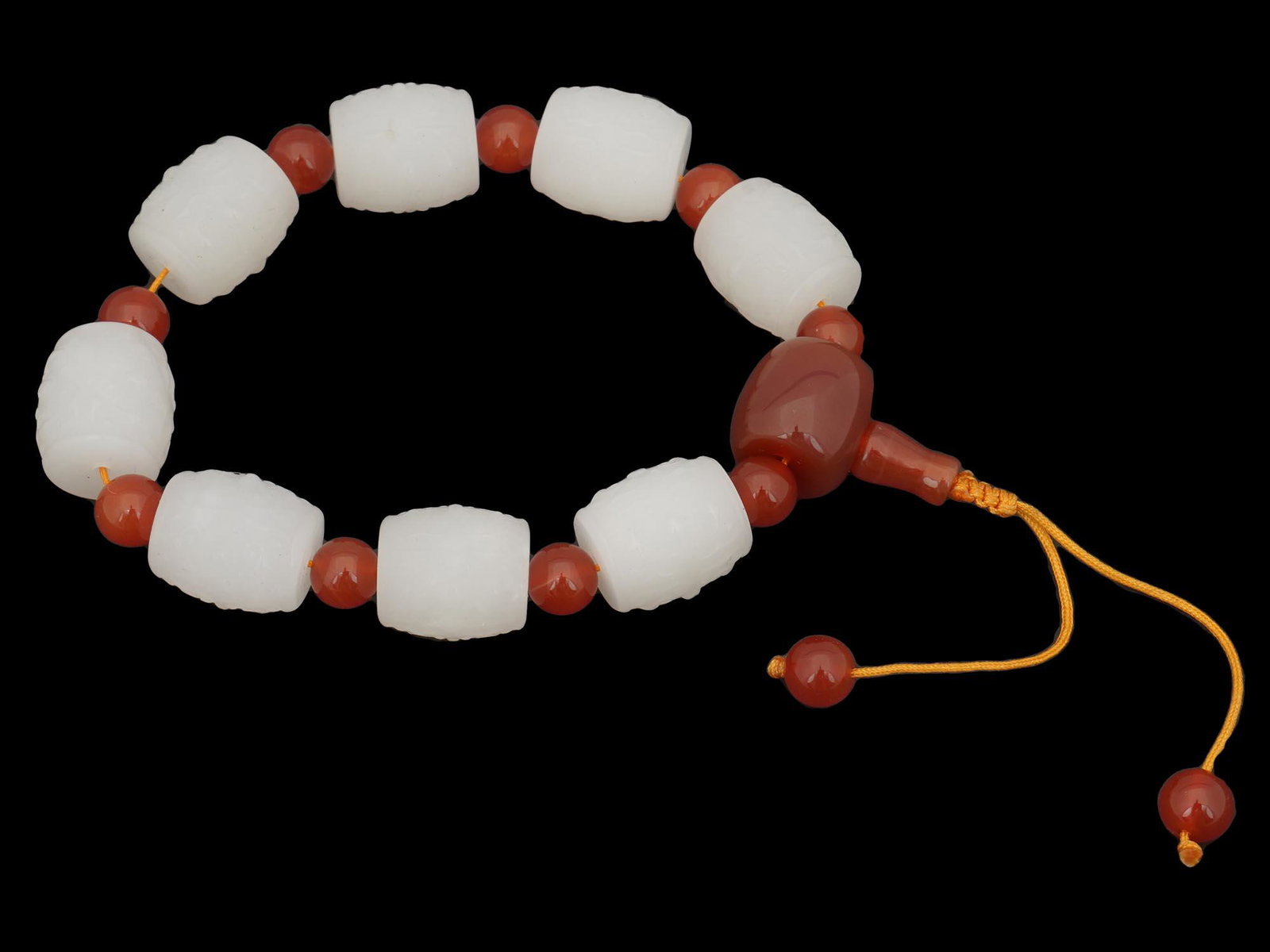CHINESE HETIAN JADE AND CARNELIAN CARVED BRACELET: A skillfully hand crafted Chinese bracelet composed of natural Hetian jade and carnelian beads. The jade beads are decorated with carved floral motifs, and the carnelian beads are nicely polished. Fen