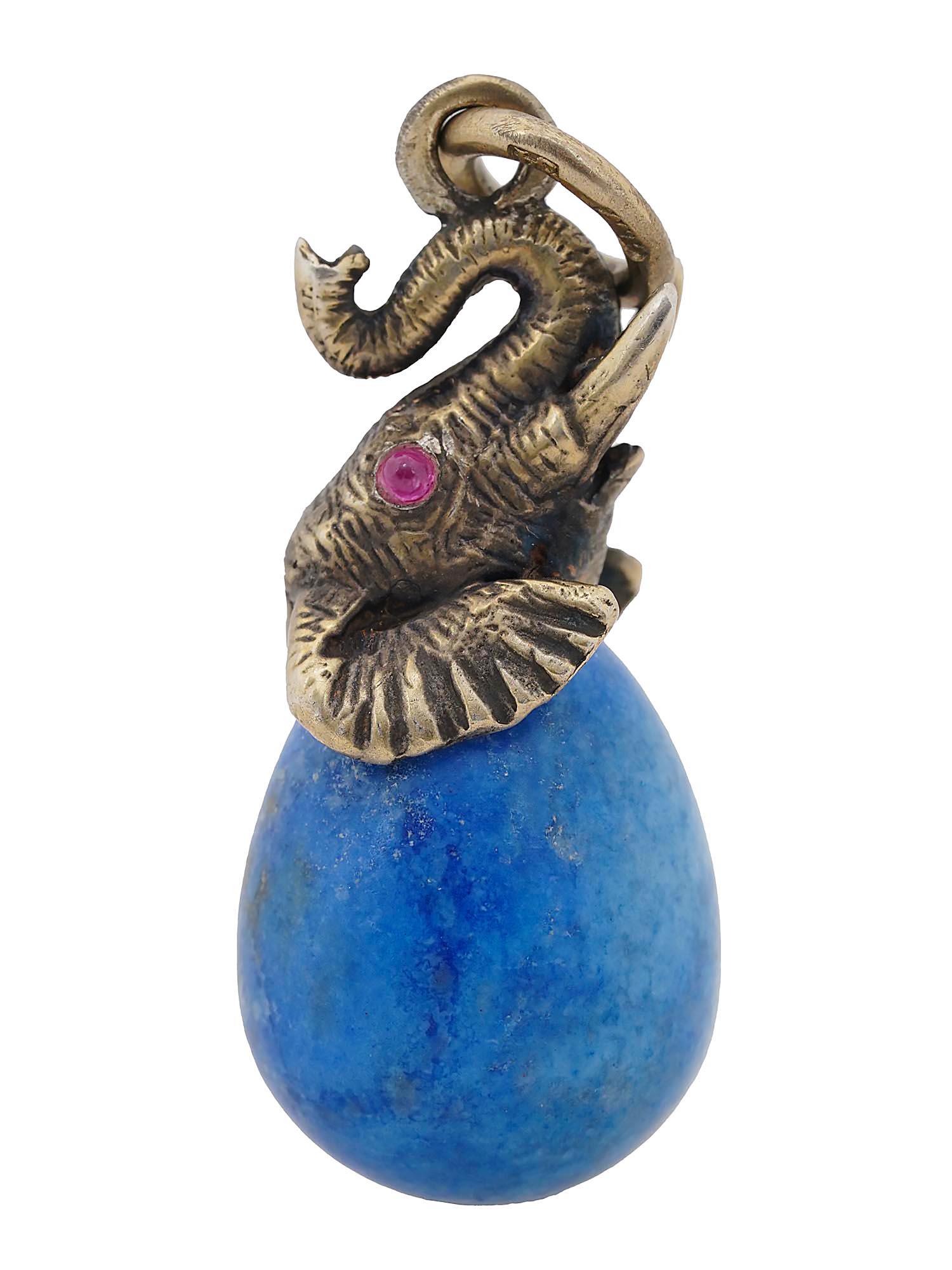 RUSSIAN SILVER LAPIS LAZULI FIGURAL EGG PENDANT: A Russian 84 gilt silver Easter Egg pendant. The egg is made from a hand carved Lapis Lazuli stone adorned with a gilt silver figurine in the shape of a head of an elephant with Ruby stone eyes on the