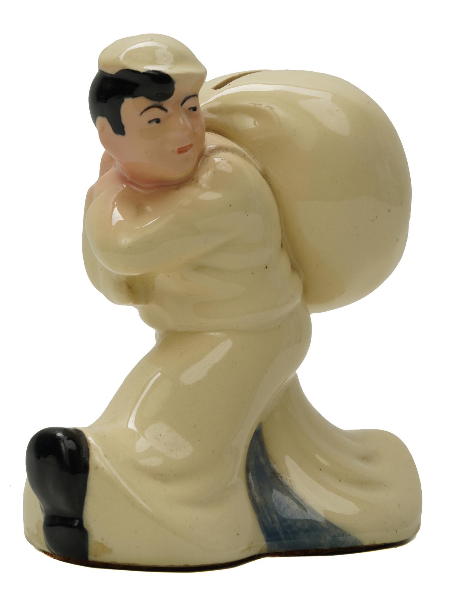 A VINTAGE PORCELAIN COIN BANK FIGURINE OF SAILOR: A vintage European figural porcelain coin bank in the shape of a sailor carrying a sack. Marked, The Seamens Bank for Savings, on the bottom. Circa:1940s-1950s. European porcelain and decor collectibl