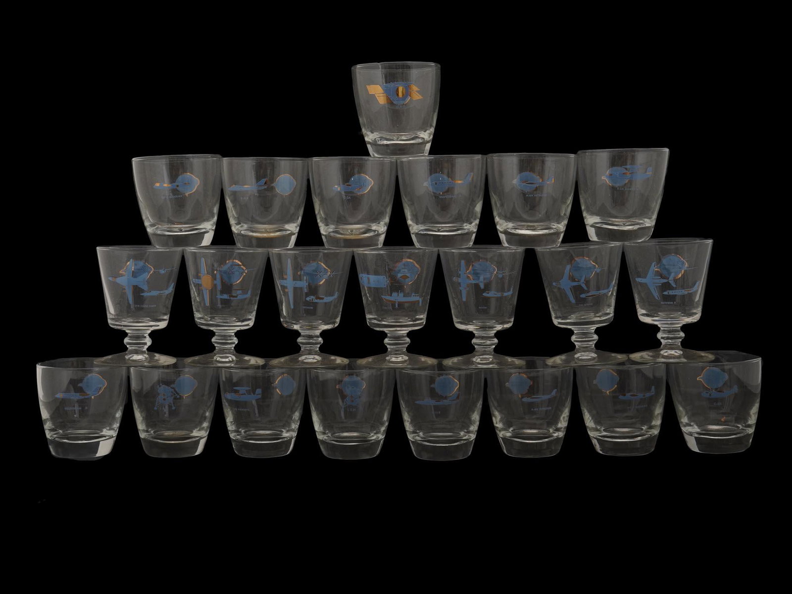 RARE VINTAGE GRUMMAN AVIATION GLASSWARE SET: A set of rare 15 vintage glass cups and 7 footed cocktail glasses with Grumman Aviation imprinted logos. Circa the 1960s or the 1970s. The Grumman Aircraft Engineering Corporation, later Grumman Aeros