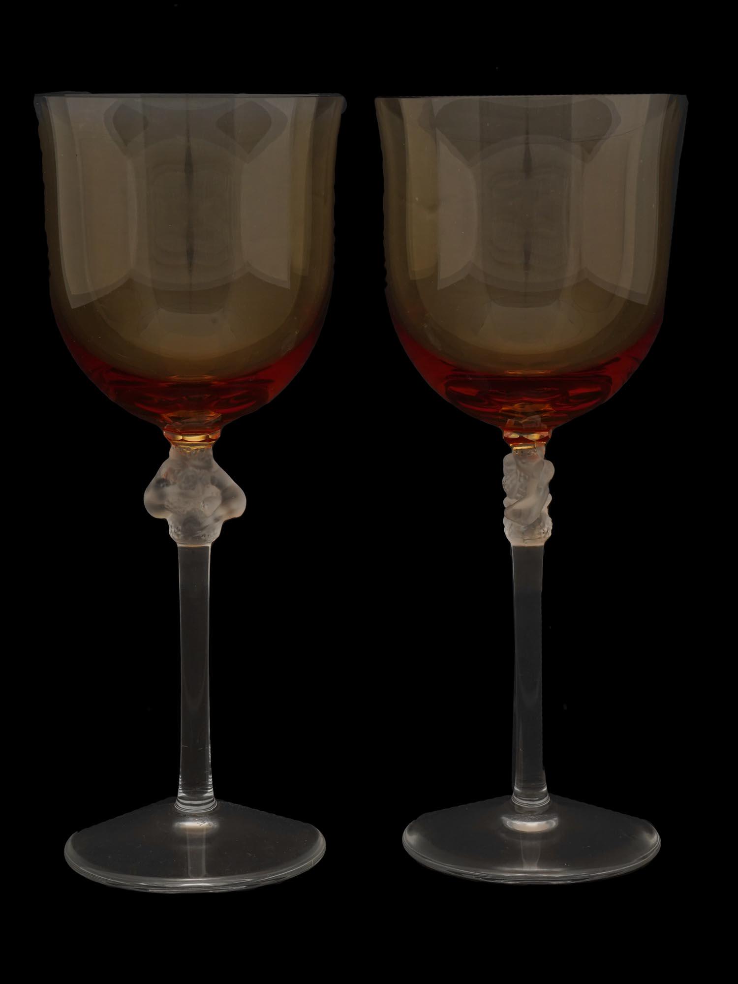PAIR OF FRENCH LALIQUE BROWN GLASS WINE STEM WARE: A pair of French Rene Lalique Roxanne gradient from brown to orange glass wine stem ware. Clear crystal glasses featuring a frosted detail of two entwined nude female figures holding grape bunches on 