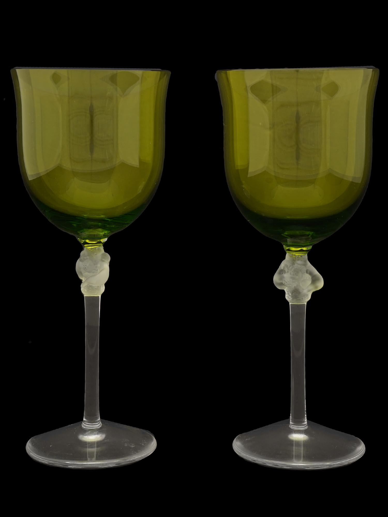 PAIR OF FRENCH LALIQUE GREEN GLASS WINE STEM WARE: A pair of French Rene Lalique Roxanne gradient from lemon yellow to green glass wine stem ware. Clear crystal glasses featuring a frosted detail of two entwined nude female figures holding grape bunch