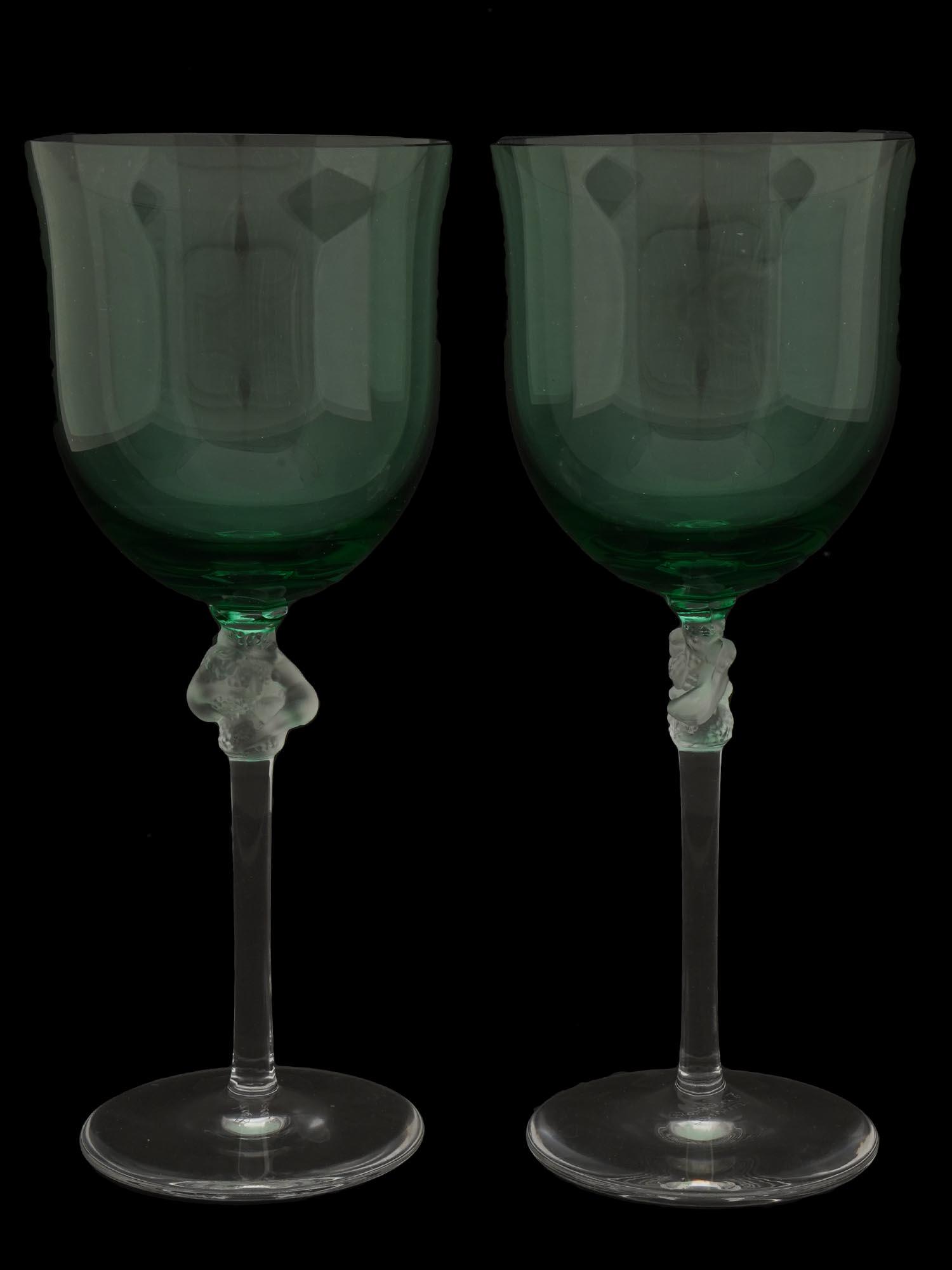 PAIR OF FRENCH LALIQUE GREEN GLASS WINE STEM WARE: A pair of French Rene Lalique Roxanne gradient green glass wine stem ware. Clear crystal glasses featuring a frosted detail of two entwined nude female figures holding grape bunches on the stem and sc