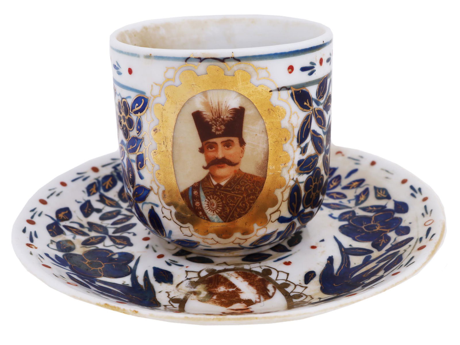 ANTIQUE PERSIAN 1800S NASER AL-DIN SHAH TEA PAIR: An antique Persian porcelain teacup and saucer from the late 19th century. Skilfully hand painted with a traditional design of leaves, flowers and birds in cobalt overglaze highlighted with gilding an