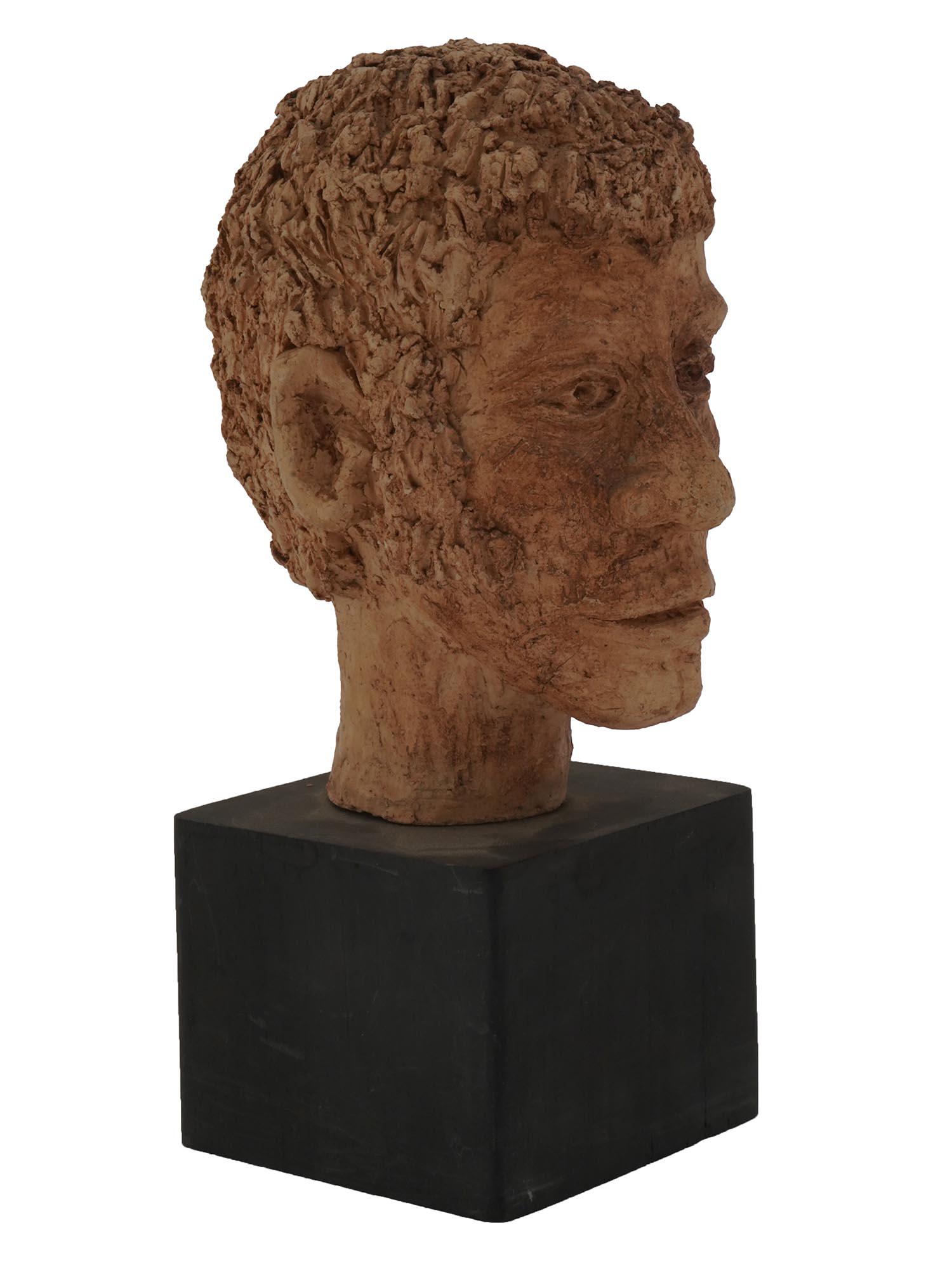 VINTAGE CLAY MALE BUST SCULPTURE: A vintage clay sculpture depicting a male bust, presumably of a savage man with short hair, an expressive nose, and big ears. On a wooden stand. Circa the late 20th century. Vintage Male Busts And Eth