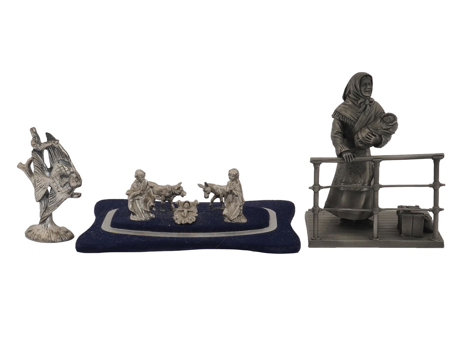 THREE PEWTER FIGURES THE FRANKLIN MINT IMMIGRANT: A lot of three vintage pewter decorative figurines. First. A multi-figure scene representing the Nativity of Christ. The figures are installed on a base lined with blue velvet. Second. A figure of a m