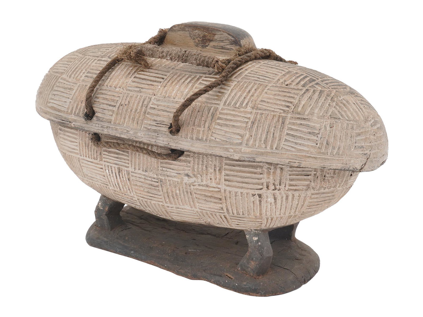 ANTIQUE AFRICAN HAND CARVED WOOD BOWL CONTAINER: An antique hand carved wood bowl container of a prolonged form with a cover and decorations throughout its body and the cover and on four feet mounted to the base. The two parts are connected with a r