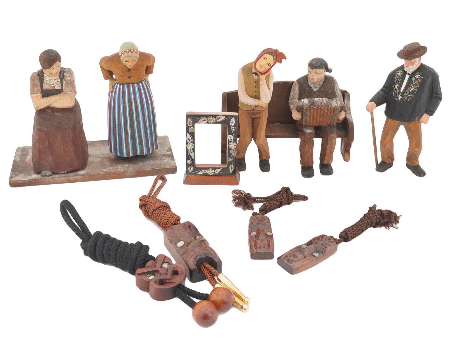 LOT OF VARIOUS WOODEN FIGURES AND MAORI PENDANTS: A collection of vintage hand crafted wooden items. The collection includes five hand carved and hand painted wooden figurines depicting human figurines in various poses, four hand carved wood New Zeal