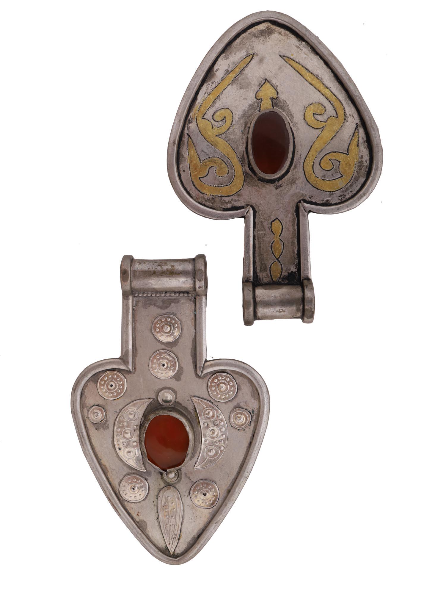 ANTIQUE 1800S SILVER CARNELIAN TURKMEN PENDANTS: A pair of antique Turkmen Asyk amulet pendants from the late 1800s. Heart shaped pendants are made of silver, highlighted with hand etched gilded design depicting stylized birds and flames, set in rai
