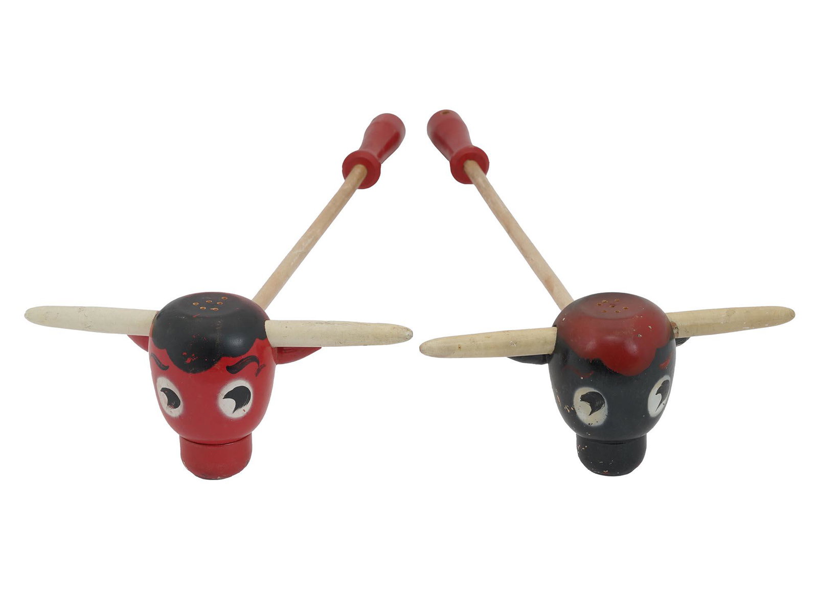 MID CENT WOODEN BULL BBQ SALT AND PEPPER SHAKERS: A set of 1950s wooden salt and pepper shakers. The red and black shakers are executed in the form of bull heads. Each piece has a long handle. Vintage Tableware And Serveware. Dimensions: L 17 1/4 in.