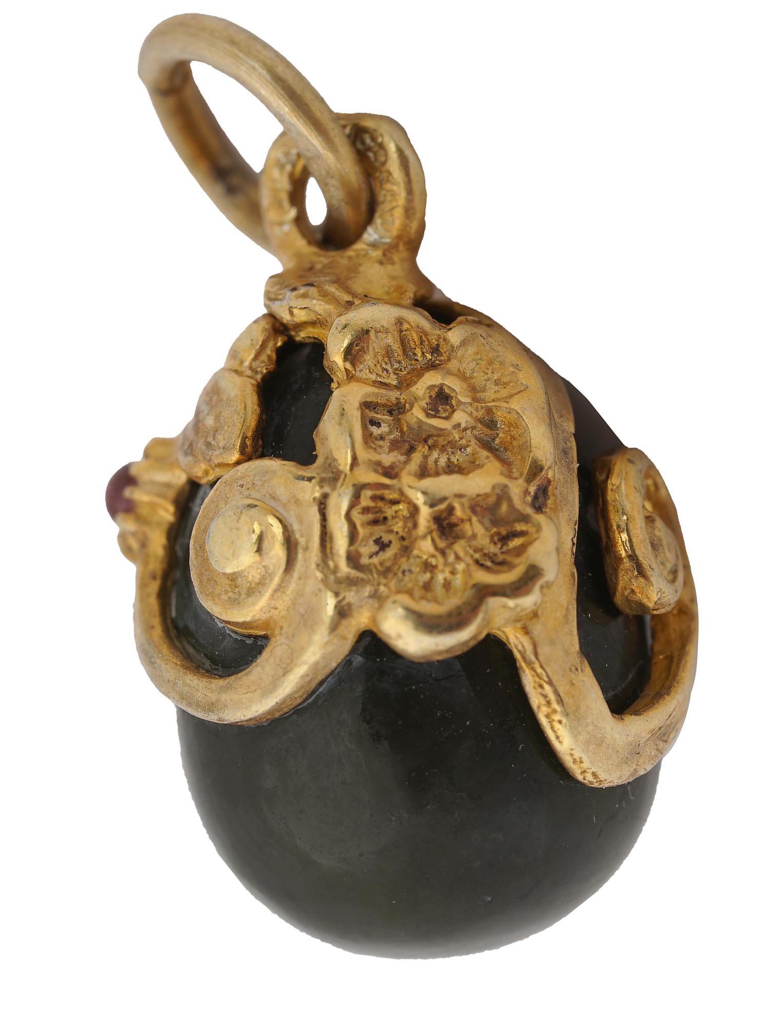 RUSSIAN SILVER GILT AND BLACK JADE EGG PENDANT: A Russian egg pendant hand carved of natural black jade housed in a beautiful silver gilt frame with embossed flowers, openwork elements and set with a ruby cabochon. Marked on the fitting ring with a
