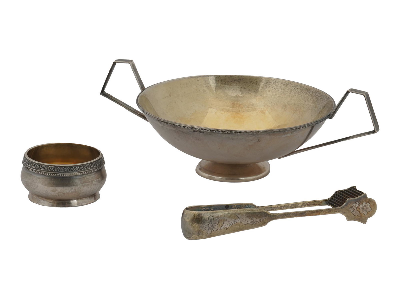 RUSSIAN SILVER BOWL, SALT CELLAR AND SUGAR TONGUE: Three Russian silverware items including a large table centerpiece with a narrow decorated rim and sharp corner handles, with a bowl consists of a large hemisphere which has been beautifully hammered 