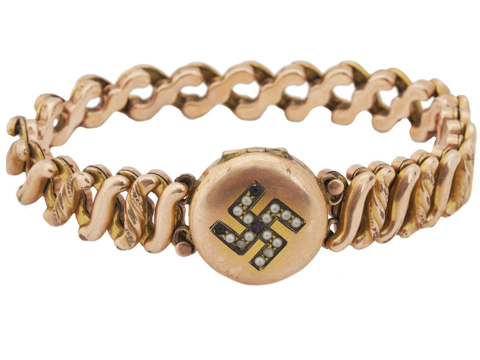 WWII GOLD LOCKET WITH PEARL SWASTIKA AND BRACELET: A Nazi German round gold locket with a hinged lid. The lid is set with small pearls forming a swastika. Engraved numeral 9 inside. The locket is set in a 1910s American gold-filled Carmen expandable l