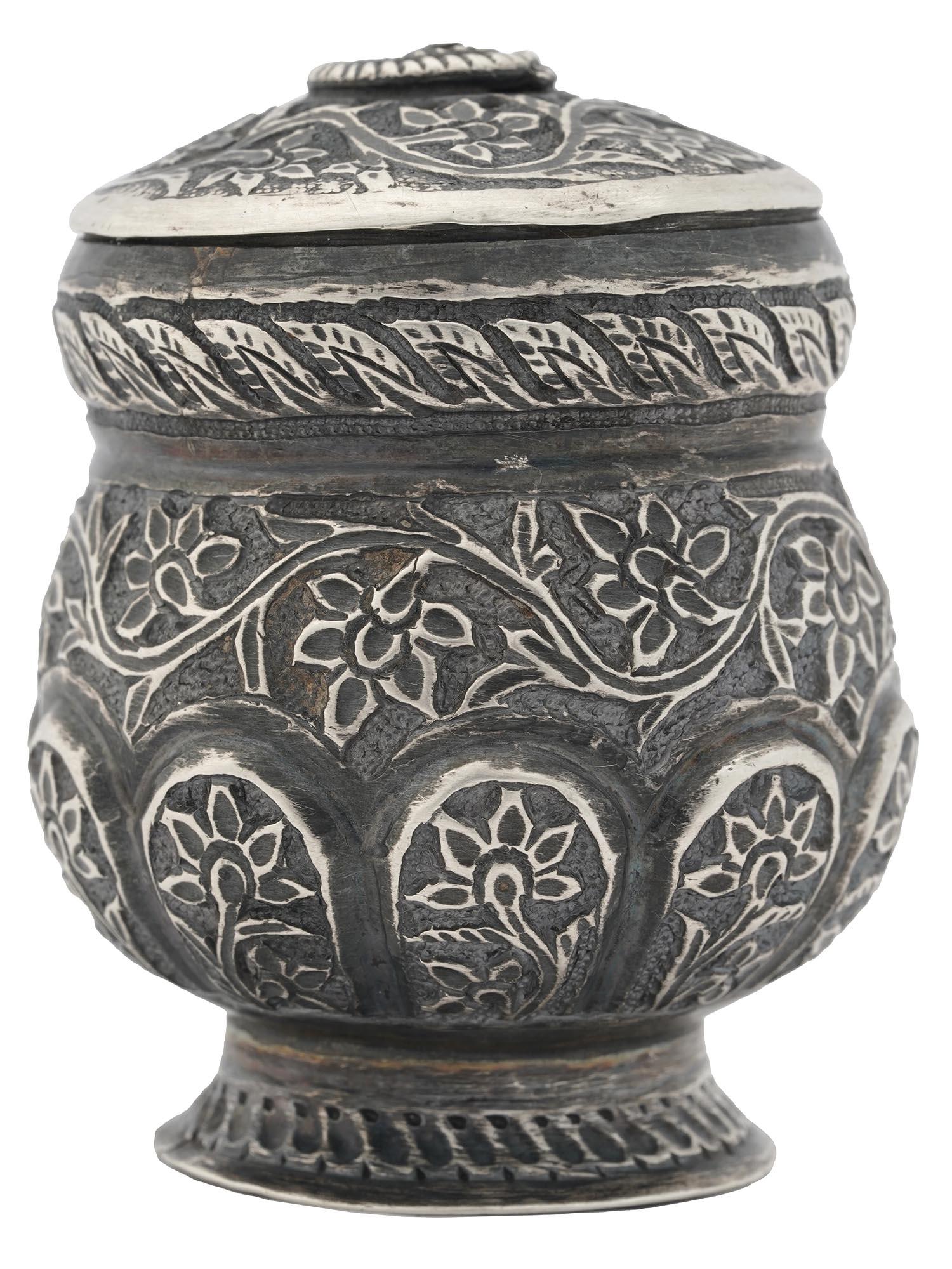 ANTIQUE INDONESIAN SILVER AND ENGRAVED SPICE BOX: An antique Indonesian covered and footed silver spice box. The exterior of the box is engraved with detailed floral and foliage patterns. The base and the neck of the box are adorned with a rope motif