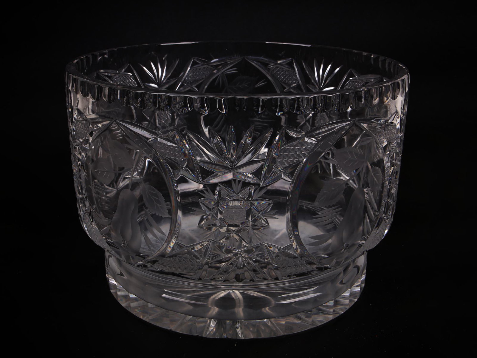ANTIQUE AMERICAN CUT GLASS BOWL CENTERPIECE: An antique American glass centerpiece bowl is cut of thick clear crystal in the American Brilliant style and engraved with fruit decorations. Dimensions: Tall 6 5/8" in. Diameter 9 1/2" in. All measur