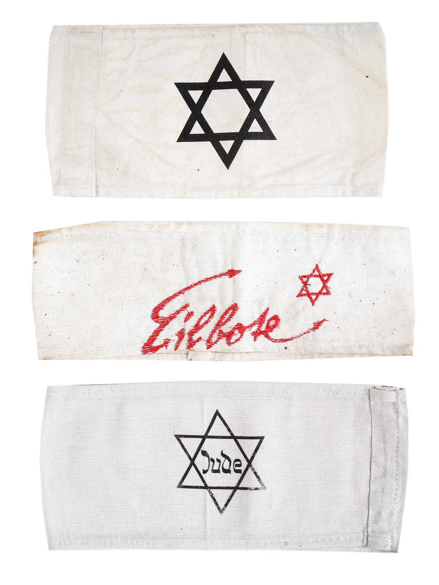 WWII HOLOCAUST JEWISH CONCENTRATION CAMP ARMBANDS: A lot of three Jewish concentration camp fabric armbands. The first has a Magen David with the inscription Eilbote, Courier. The second has a Magen David with the inscription Jude, Jew. The third has 