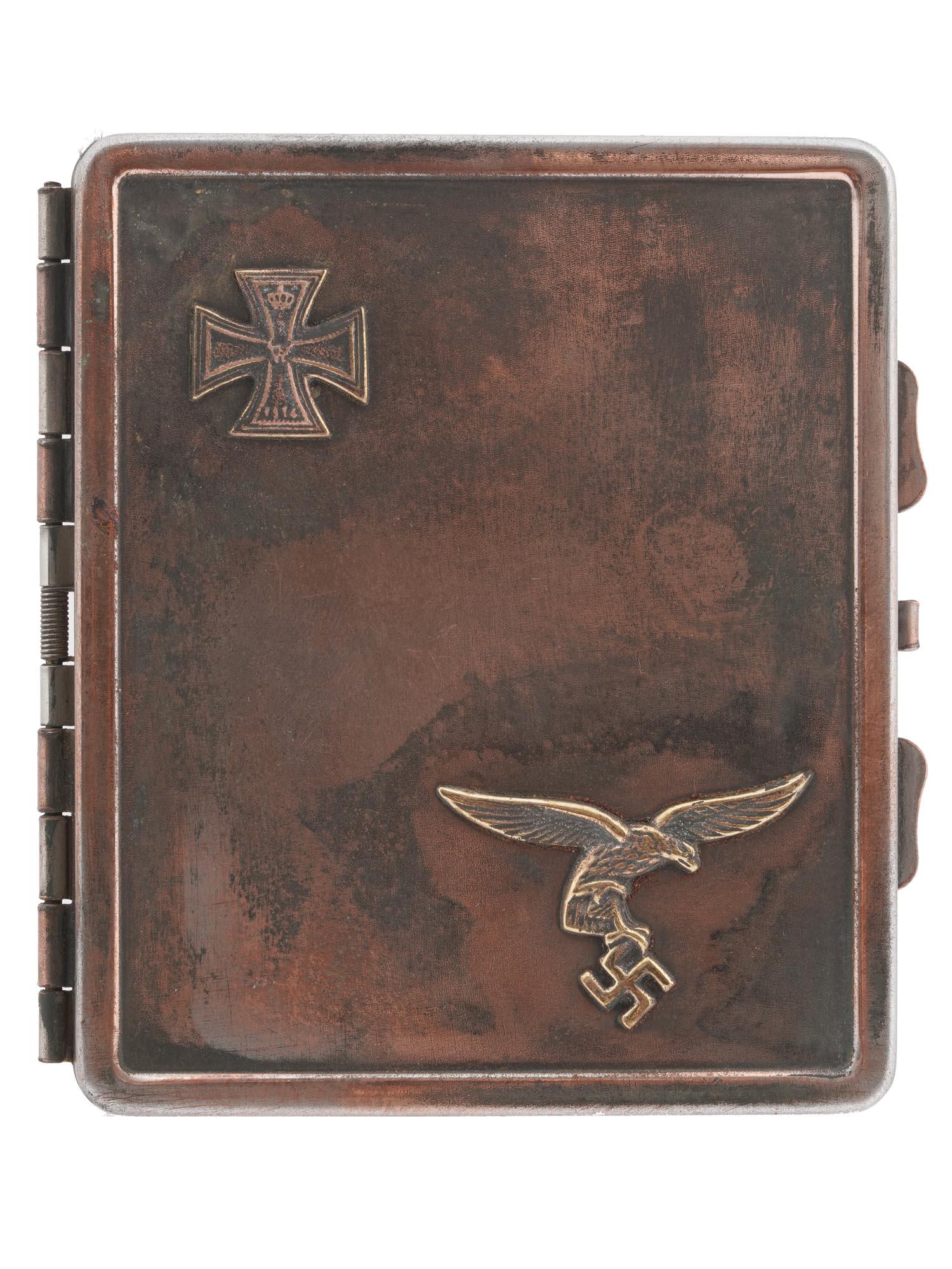 WWII NAZI GERMAN LUFTWAFFE PILOTS CIGARETTE CASE: A WWII German metal cigarette case with a hinged lid. The lid is decorated with relief Luftwaffe and Iron Cross emblems. The backside of the case has a ribbed surface. The spring inside of the item is