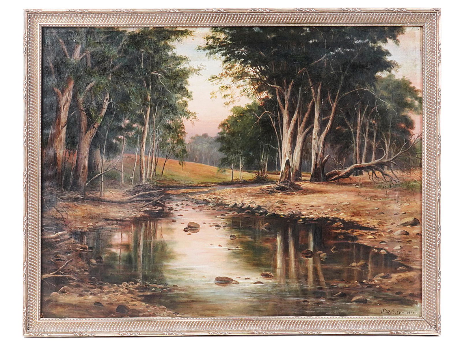 1913 AUSTRALIAN LANDSCAPE PAINTING BY JOHN WOOLER: John Wooler, South Australian, 20th century, oil on canvas landscape painting depicting a wooded river bed landscape scene in South Australia. Signed by the artist lower right and dated 1913. Framed.