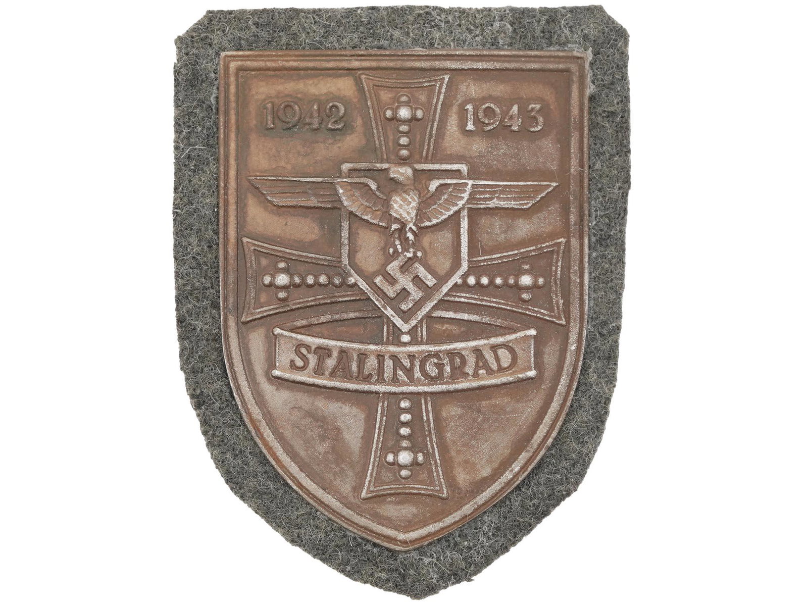 WWII NAZI GERMAN MILITARY AWARD STALINGRAD SHIELD: A World War II German military decoration, the Stalingrad Shield. The zinc shield-shaped badge features an eagle with with swastika, a cross and inscription 1942-1943 Stalingrad. The Battle of Staling