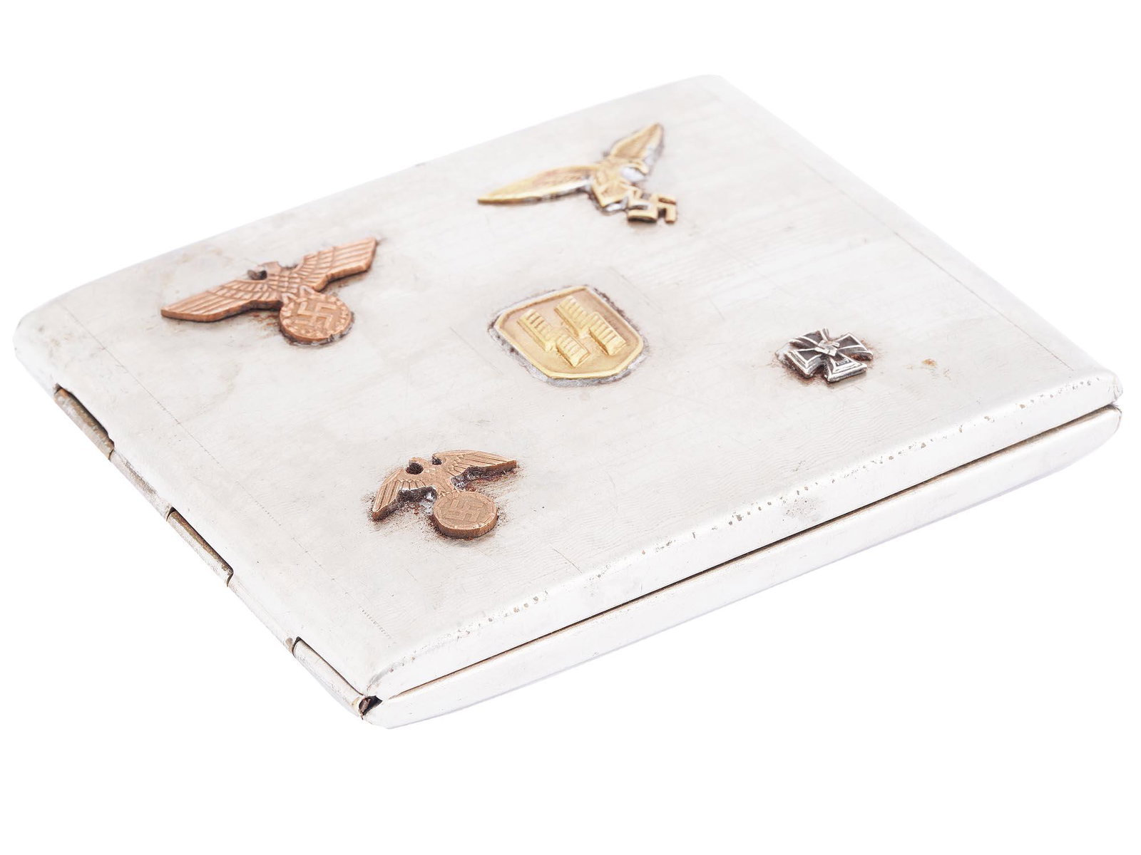 WWII NAZI GERMAN WAFFEN SS HINGED CIGARETTE CASE: A WWII Nazi German silver-tone cigarette case with a hinged flap. Relief SS emblem, eagles with a swastika, and a cross decorate the lid. The piece is hilt inside and has two holding straps. The Schut