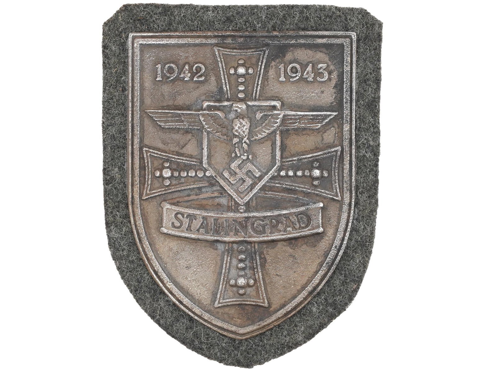 WWII NAZI GERMAN MILITARY AWARD STALINGRAD SHIELD: A World War II German military decoration, the Stalingrad Shield. The zinc shield-shaped badge features an eagle with with swastika, a cross and inscription 1942-1943 Stalingrad. The Battle of Staling