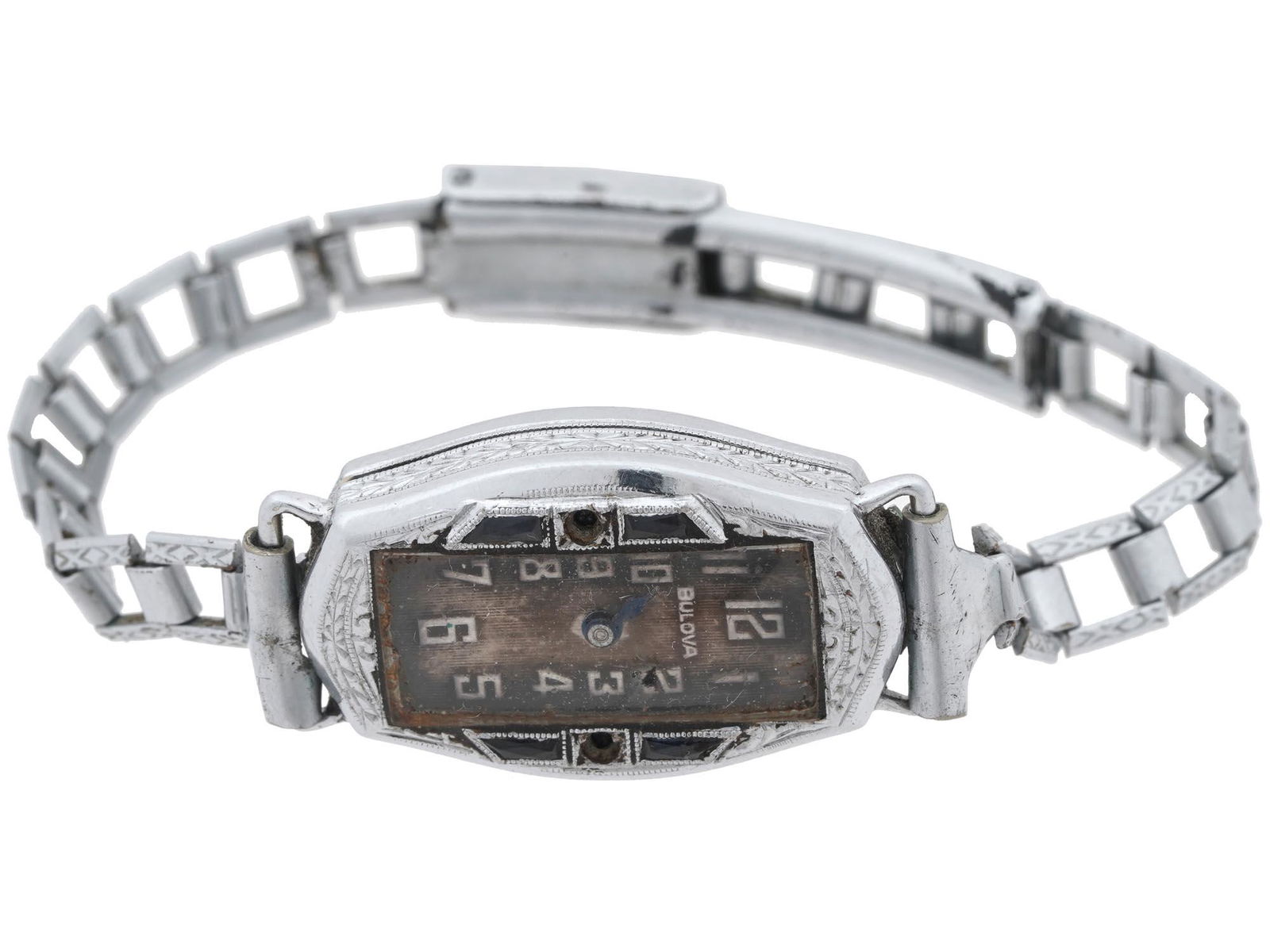 ANTIQUE BULOVA 14K WHITE GOLD WOMENS WRIST WATCH: An antique early 20th-century 14K white gold writstwatch. Elongated bezel with embossed floral ornaments and faceted black sapphires. Rectangular dial with Arabic numerals. Link bracelet with square c