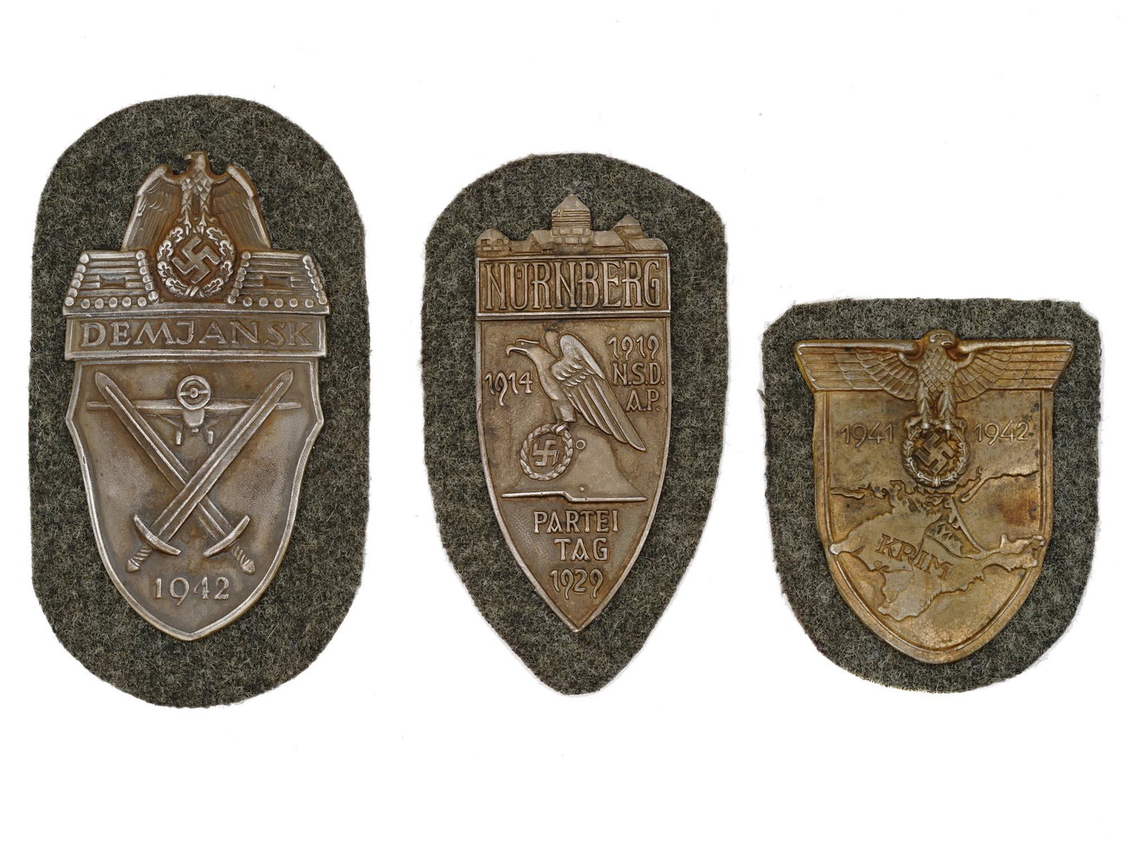 WORLD WAR II NAZI GERMAN MILITARY SHIELDS 3 PCS: A group of three World War II German military decorations including such military decorations as a Demyansk Shield featuring an eagle with swastika, flanked by two log pillboxes with gun ports and ins
