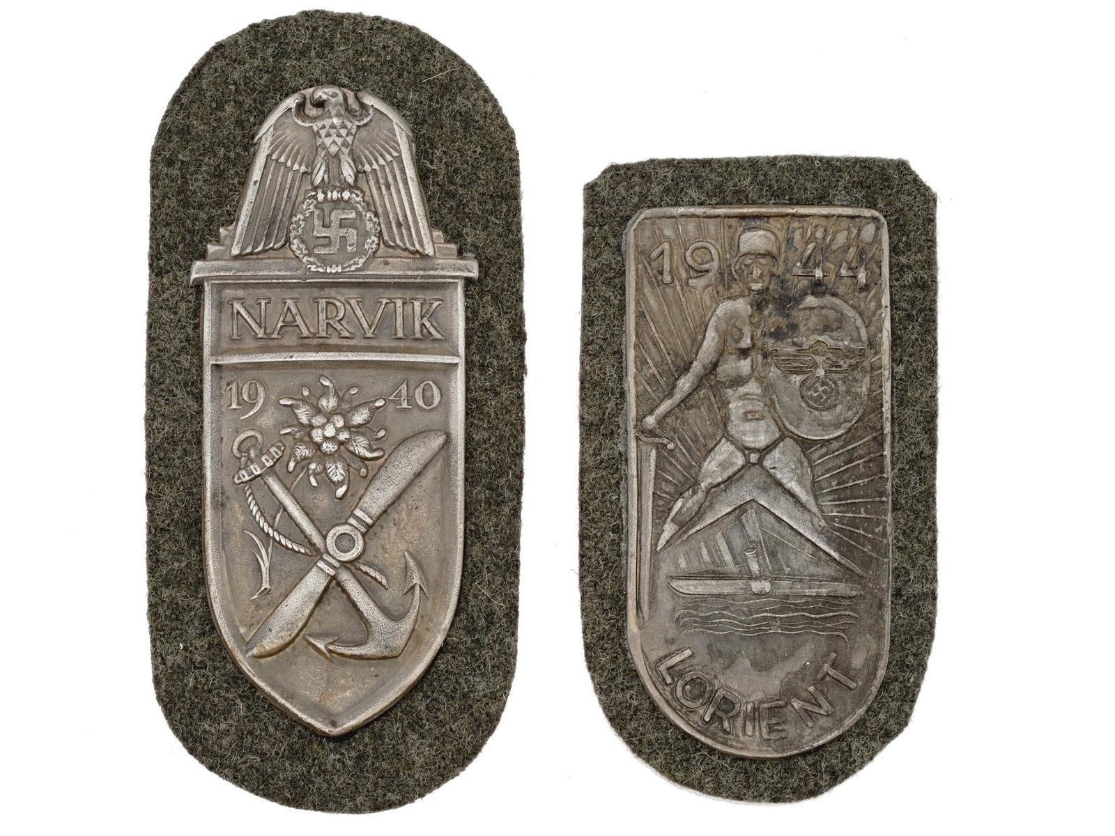 WWII NAZI GERMAN MILITARY NARVIK LORIENT SHIELDS: A pair of World War II German military decorations, the Narvik Shield and the Lorient Shield. The Narvik Shield features an eagle with down swept wings clutching a laurel wreath that surrounds a swast