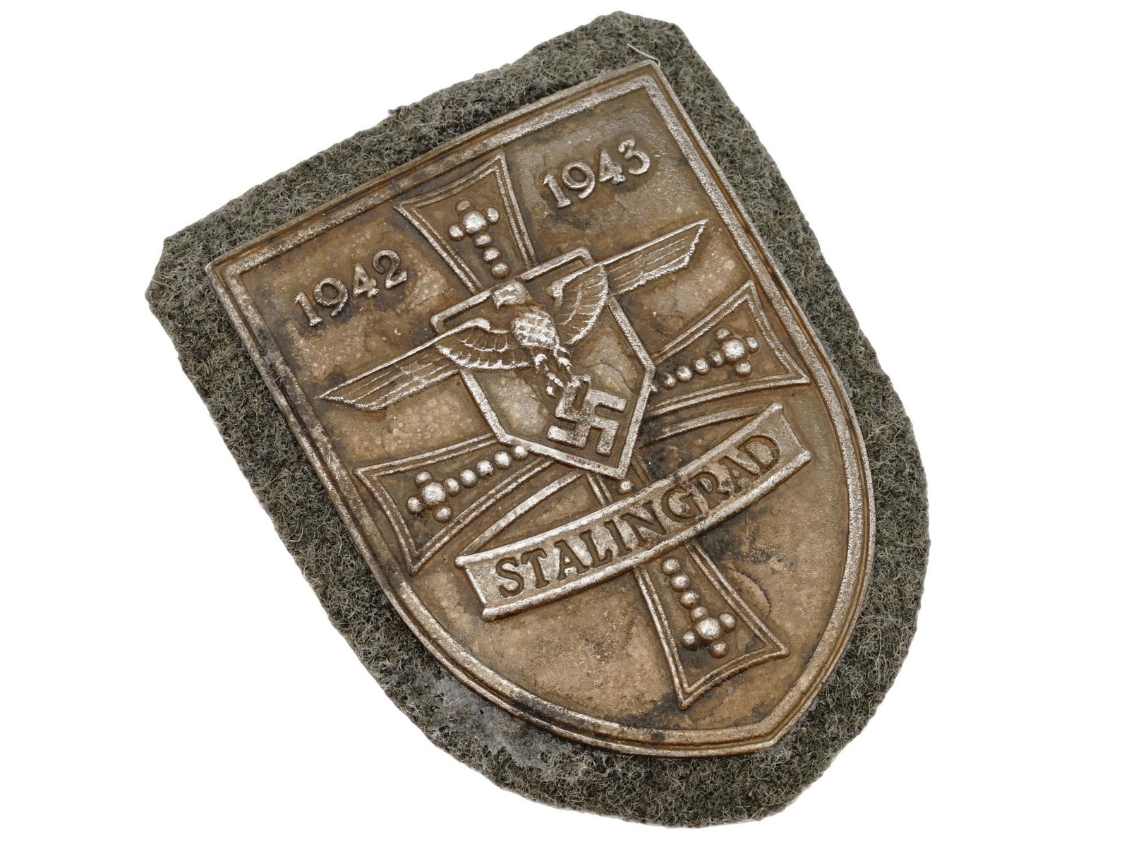 WWII NAZI GERMAN MILITARY AWARD STALINGRAD SHIELD: A WWII Nazi German military decoration, the Stalingrad Shield. The zinc shield shaped badge features an eagle with swastika, a cross and inscription 1942 to 1943, Stalingrad. The Battle of Stalingrad 