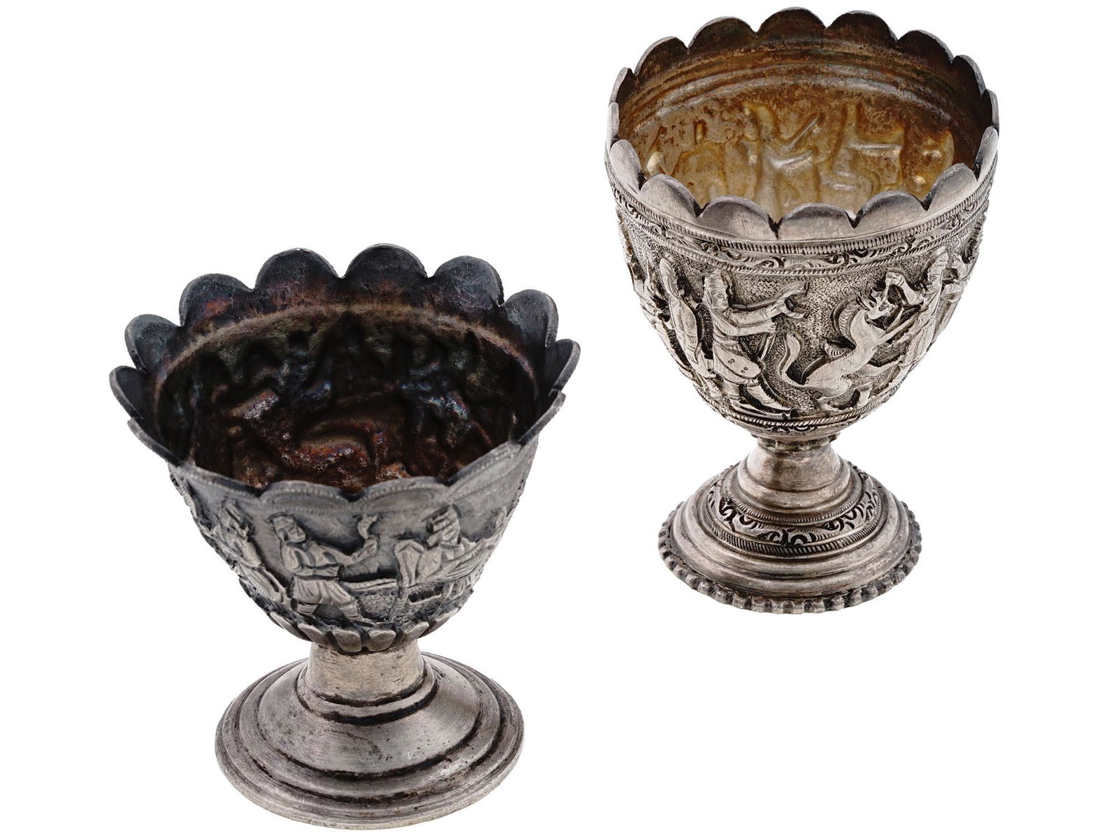 ANTIQUE PERSIAN QAJAR STERLING SILVER EGG CUPS: A pair of antique Persian silver footed cups or goblets. Qajar Empire, 1795 to 1925. Egg shape with figurative rims. The pieces are decorated with chased reliefs representing multi-figure royal proces