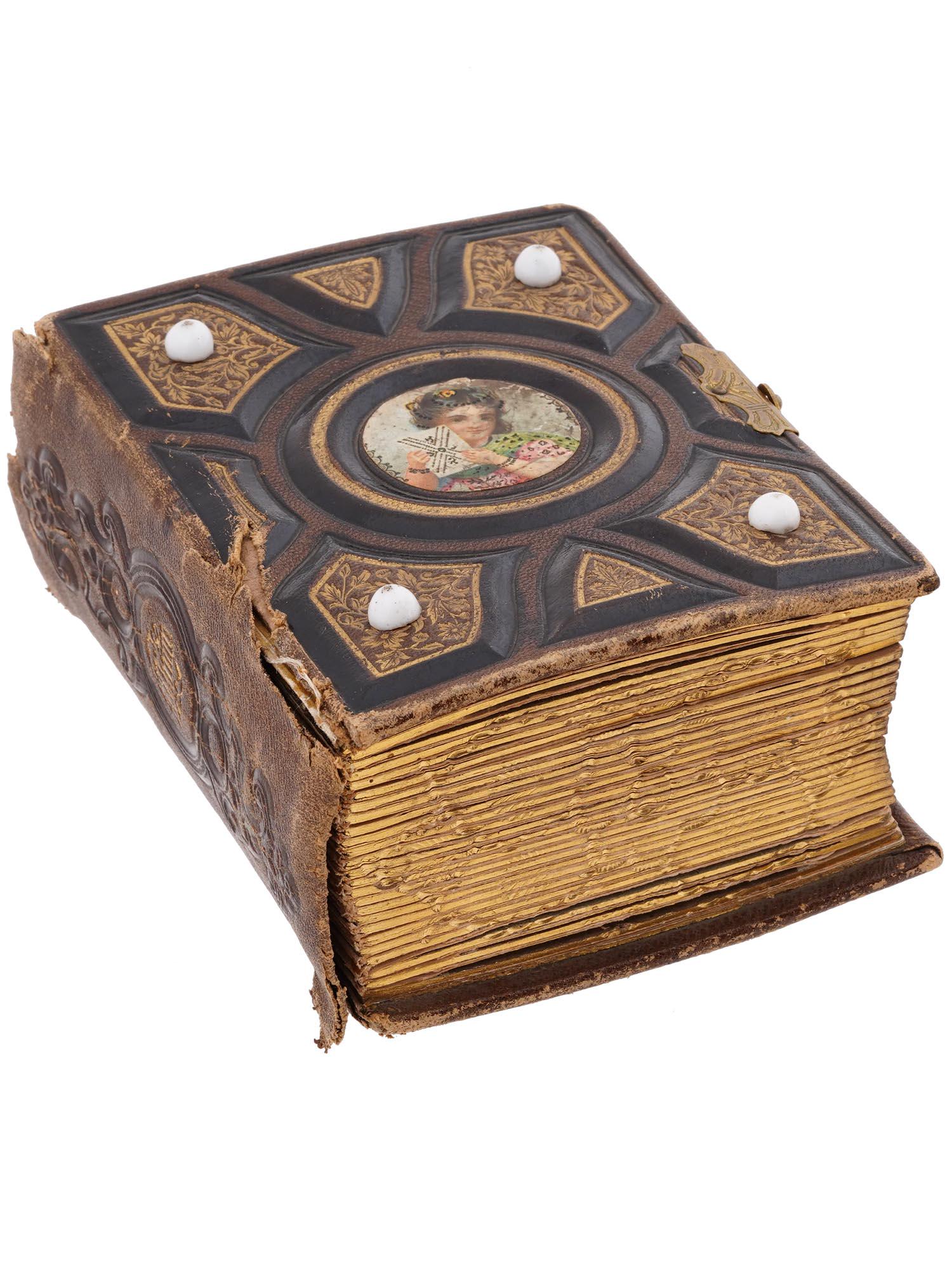 ANTIQUE LEATHER PHOTO ALBUM WITH PORTRAIT PHOTOS: An antique photo or picture album with a gilt metal clasp. Made of leather. The cover is adorned with embossed scrollwork and foliage patterns, and a portrait of a lady holding a letter in the Rococo 