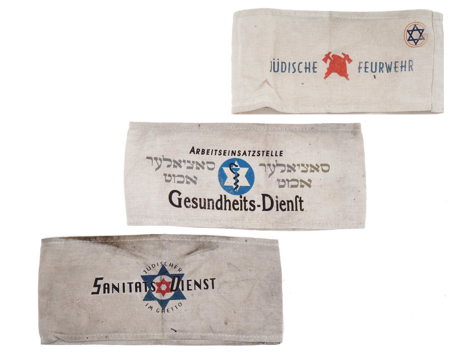 GROUP OF 3 HOLOCAUST JEWISH GHETTO ARMBANDS: A collection of three World War II Jewish Holocaust Ghetto armbands. The collection includes a Jewish Fireman armband, and a pair of Ghettos Jewish Medical Service armbands, inscribed Sanitats Dienist
